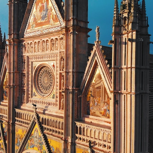 一个哥特式大教堂的正面，装饰华丽，彩色玻璃窗和展示宗教场景的精美马赛克。