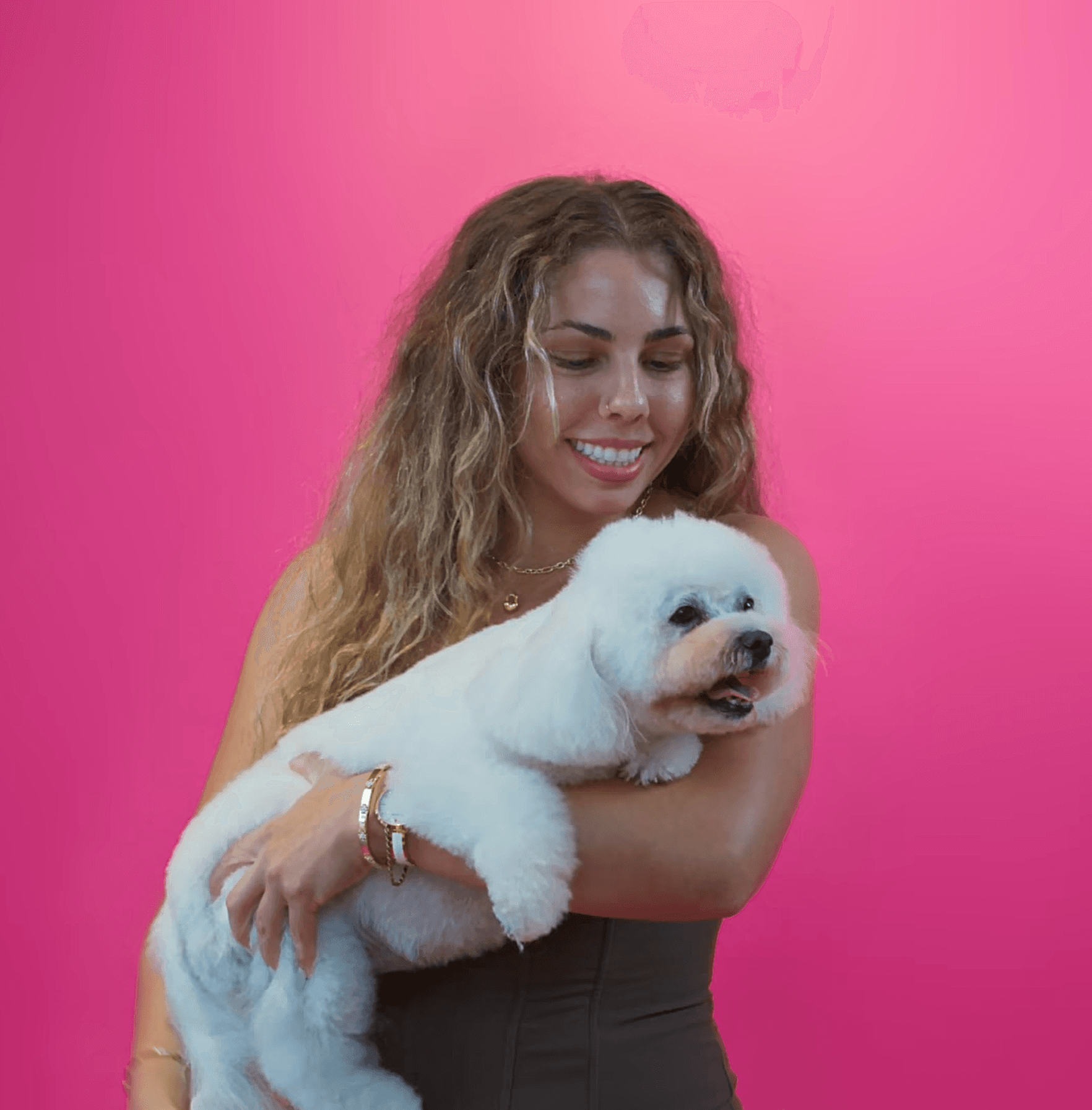 Smiling woman holding a freshly groomed white dog to express happiness, care, and confidence after a grooming session.
