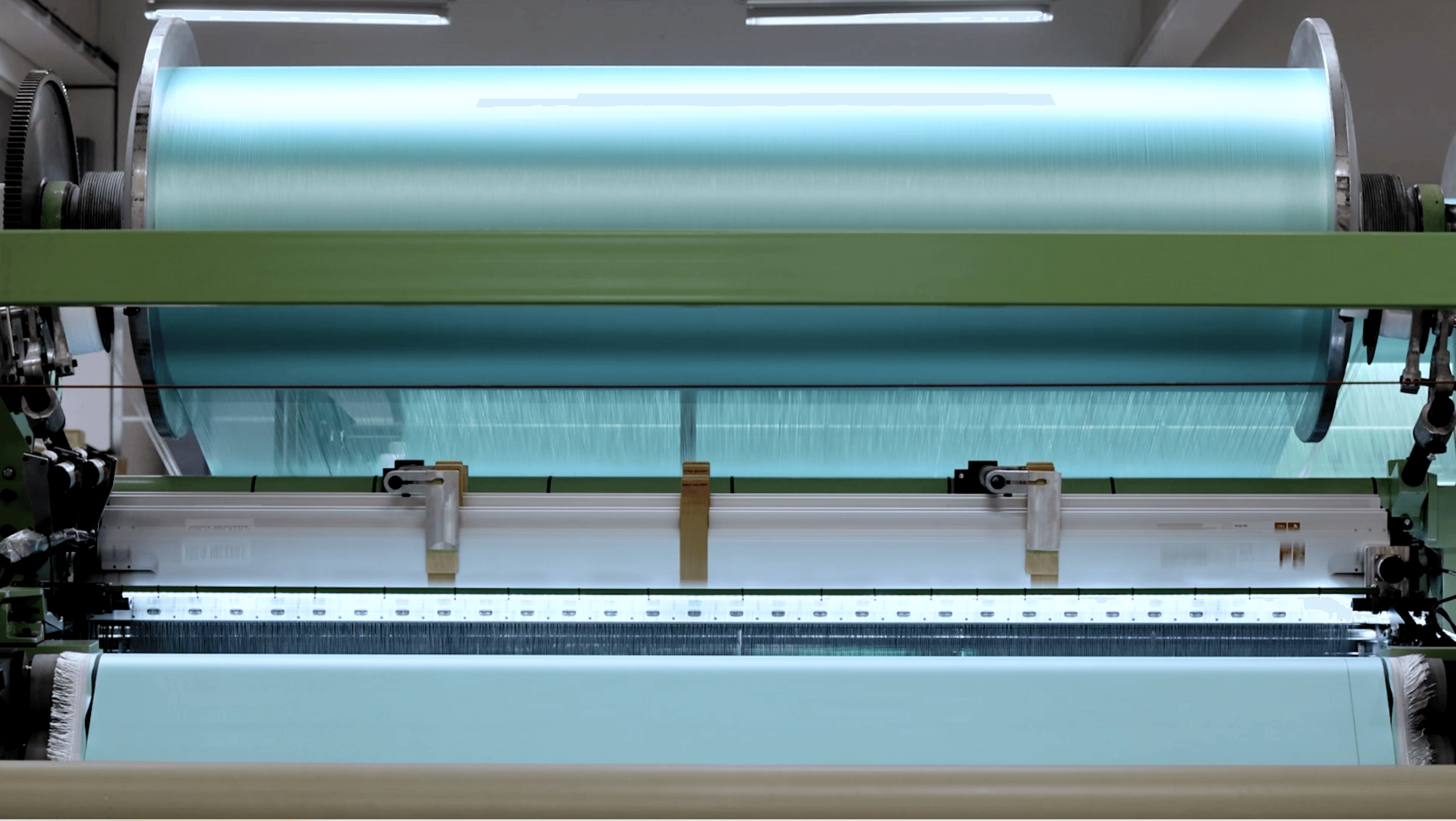 A close-up view of a roller machine with blue and green sections, used in manufacturing or processing.