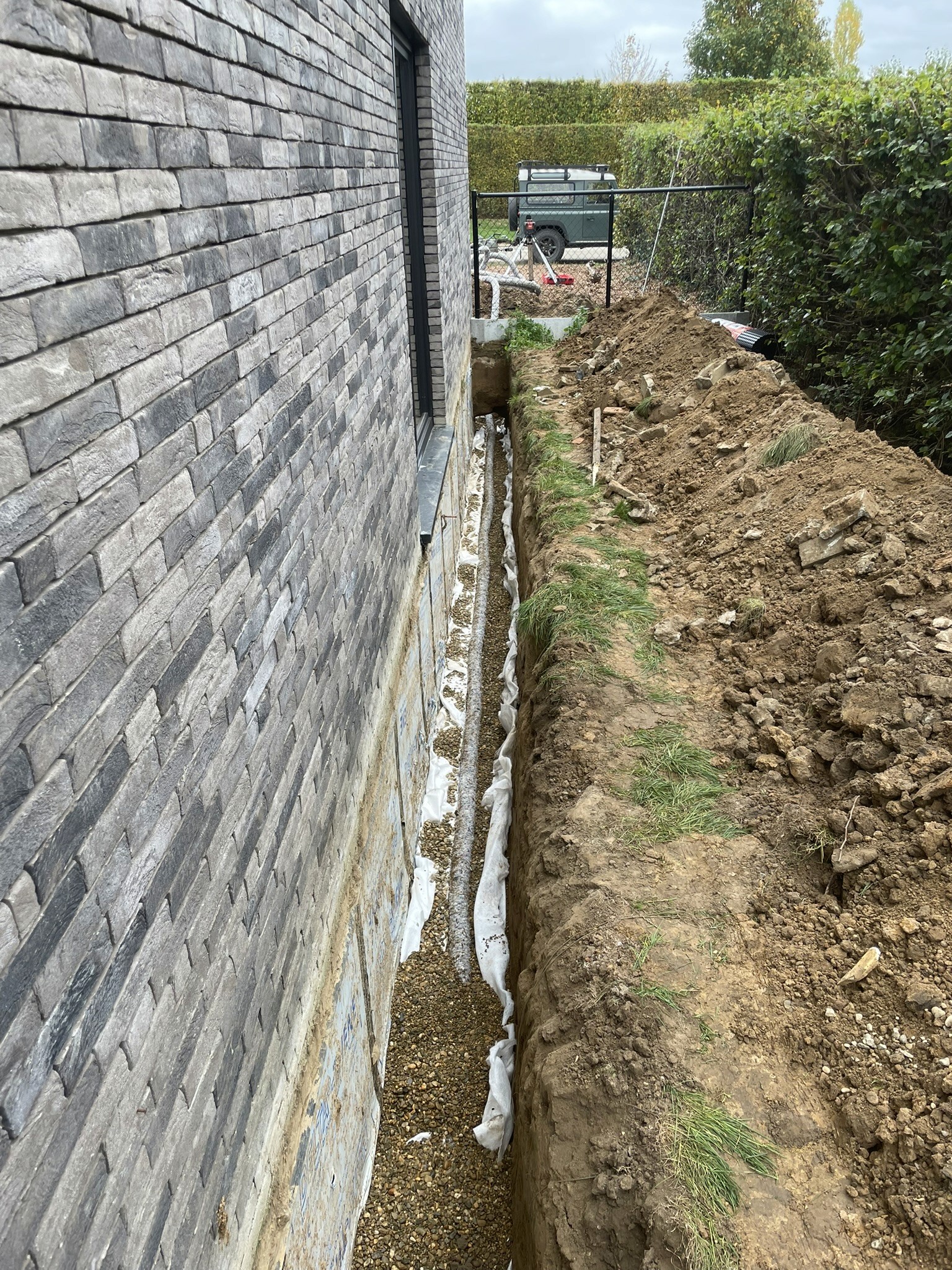 Plaatsen van drainage tegen woning — Tuinaanleg in Lubbeek, gerealiseerd door Wilmaerts Tuinaanleg