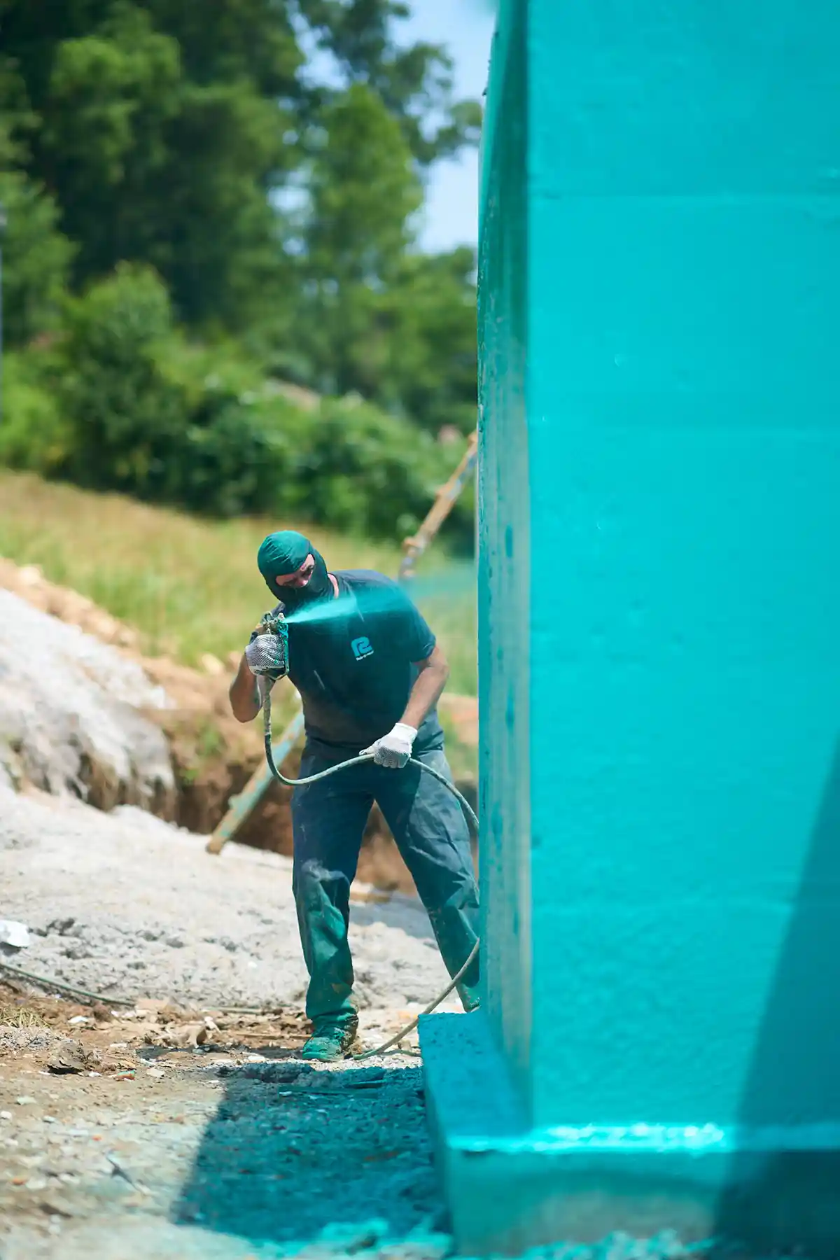 A waterproofing applicator spraying Rub-R-Wall onto an ICF foundation