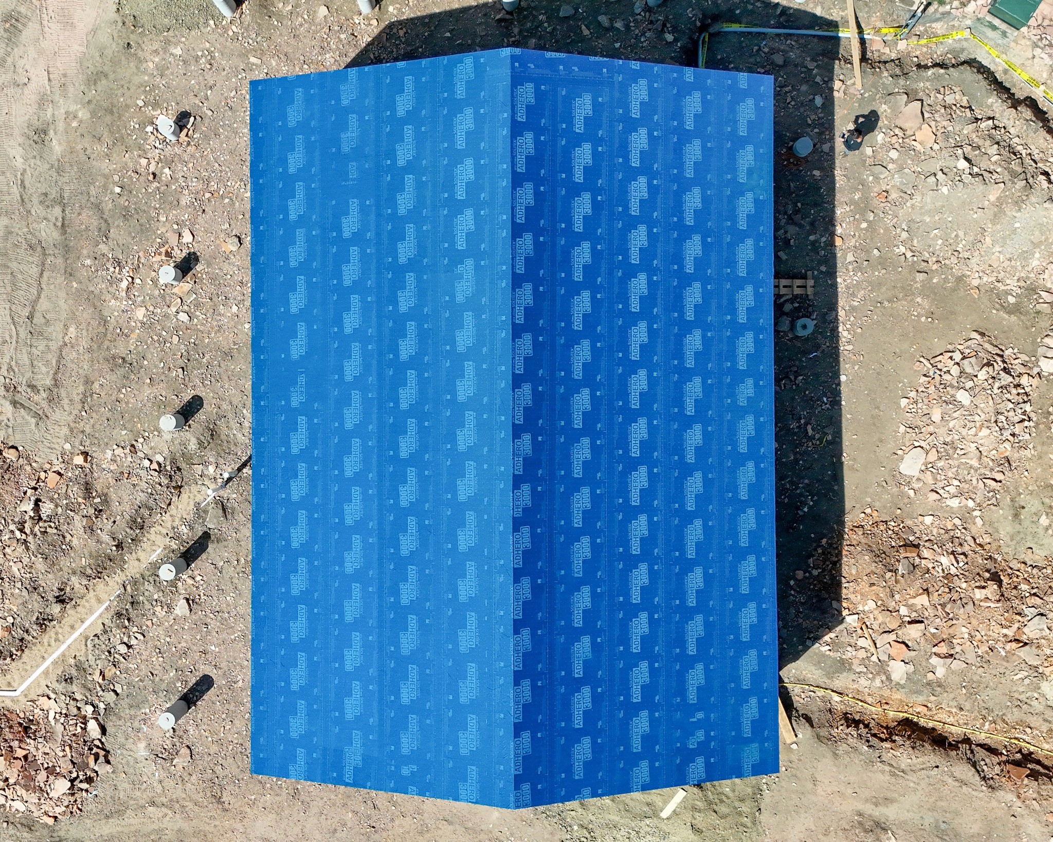Overhead aerial view of the Ridge House under construction in Lyons, Colorado, wrapped in a blue weather barrier.