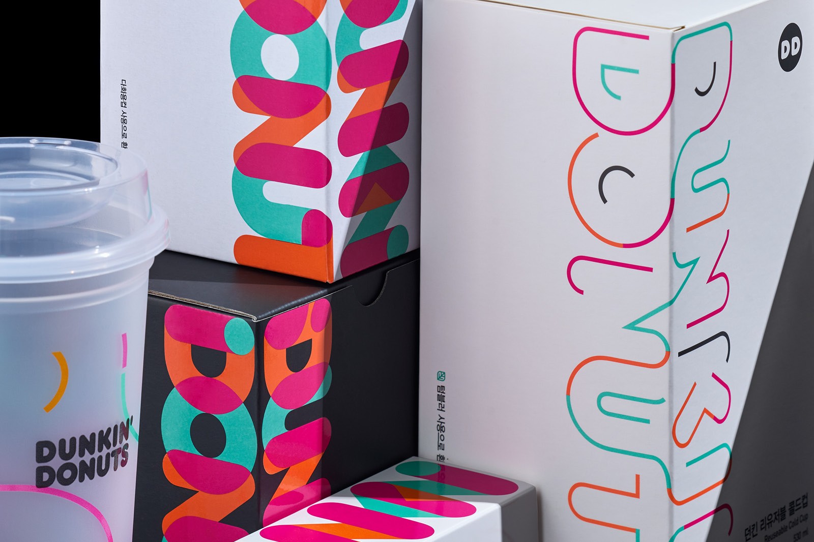 A stylish display of colorful Dunkin' Donuts  packaging and a drink cup on a table, showcasing modern design elements.