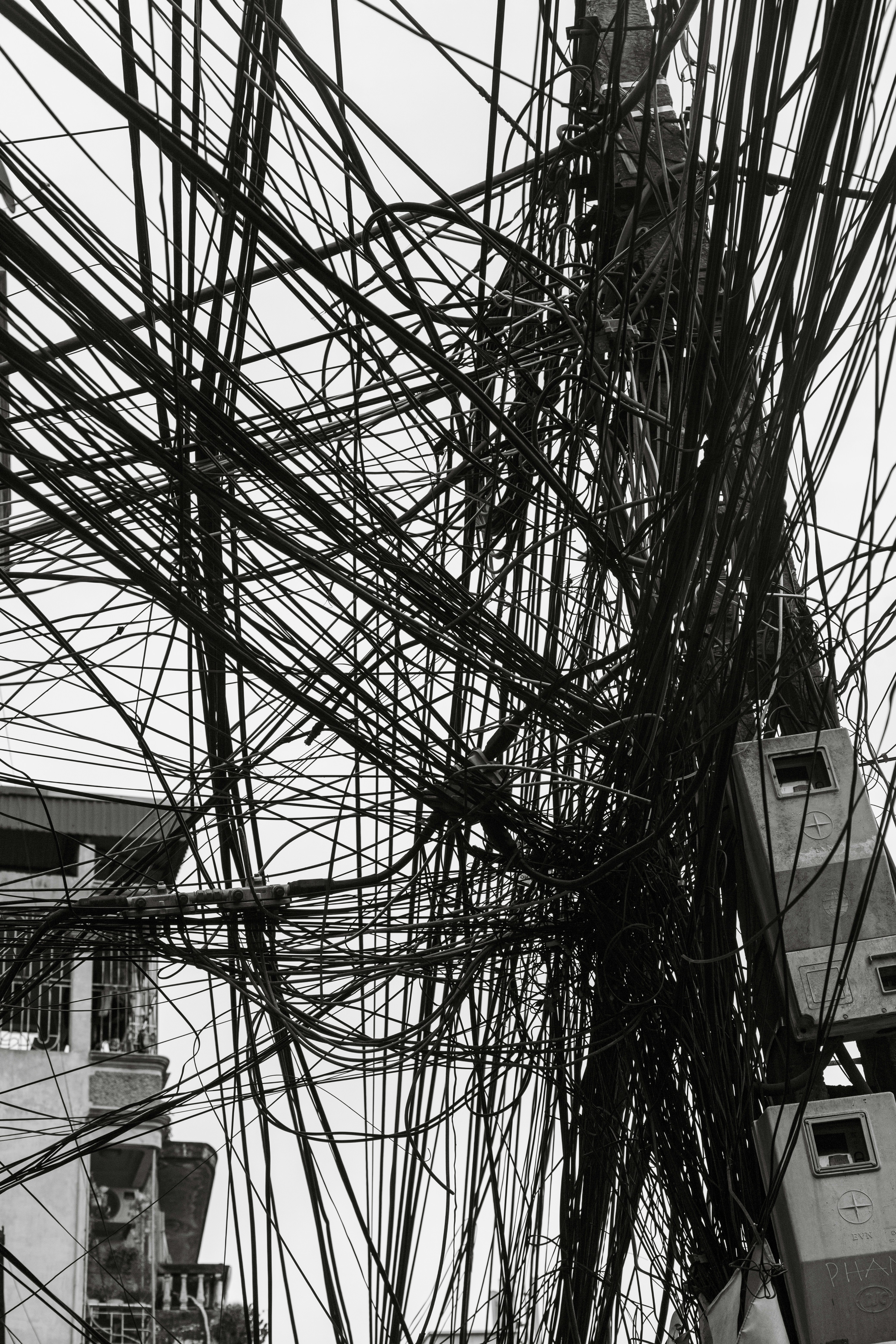 A dense tangle of electrical wires against a bright sky.