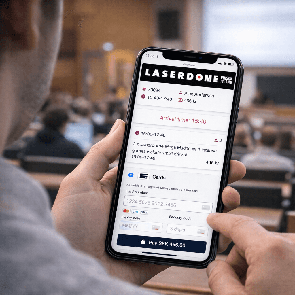 A young person with curly hair smiles at the camera while sitting in front of a laptop against a dark background.