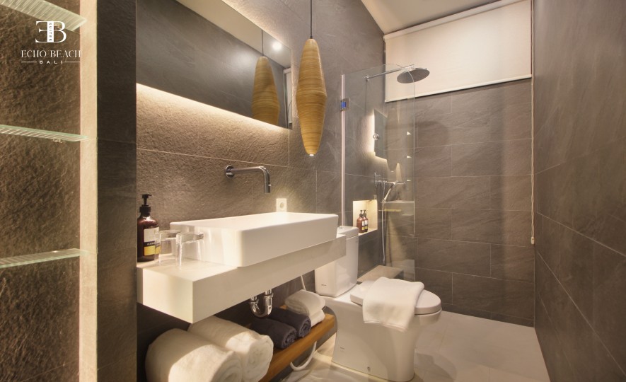 Modern, well-lit bedroom featuring a work desk and access to one of the three bathroom facilities in the Echo Beach Suite apartment, Bali.