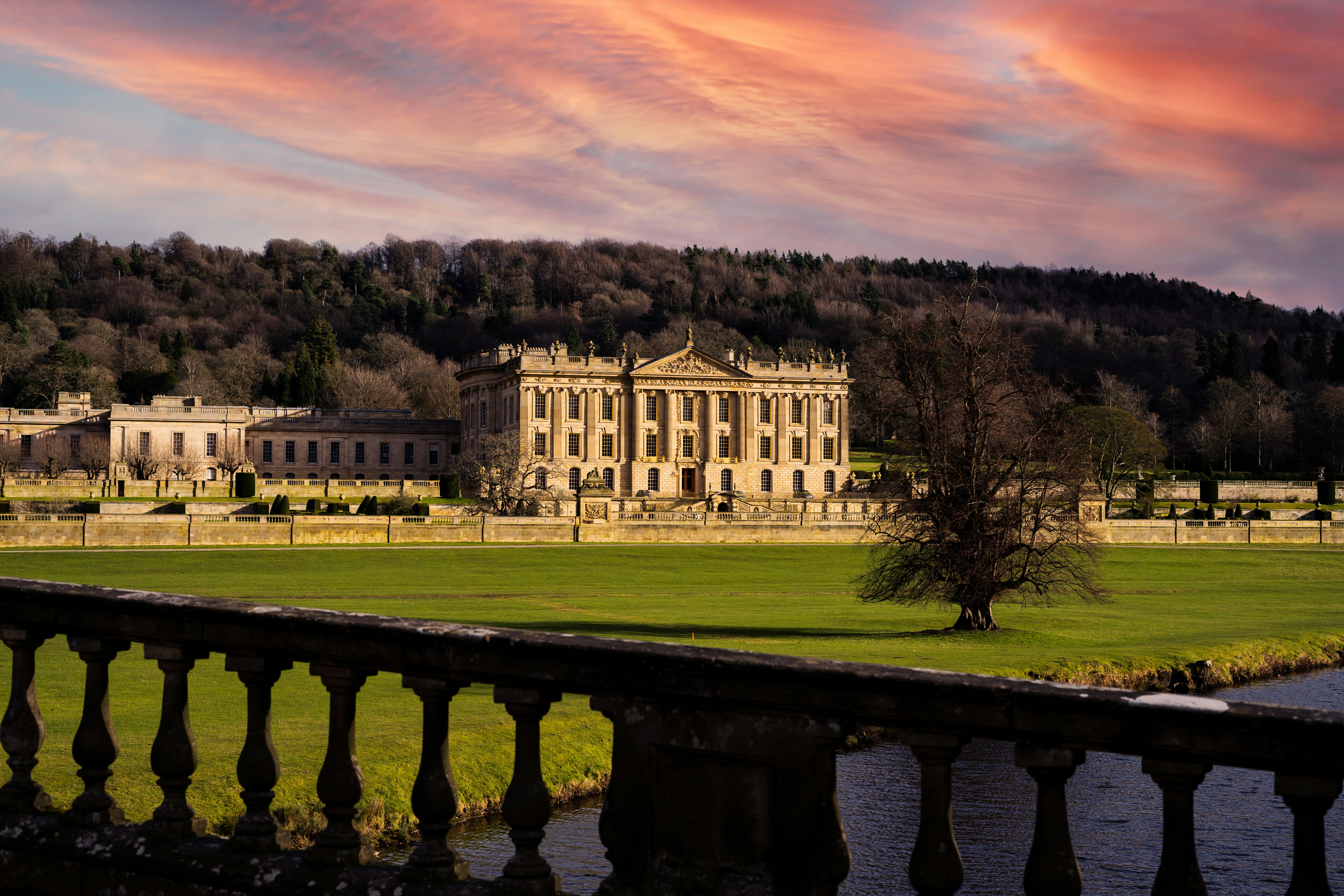 A wide exterior shot of a royal-style building with its surrounding garden.
