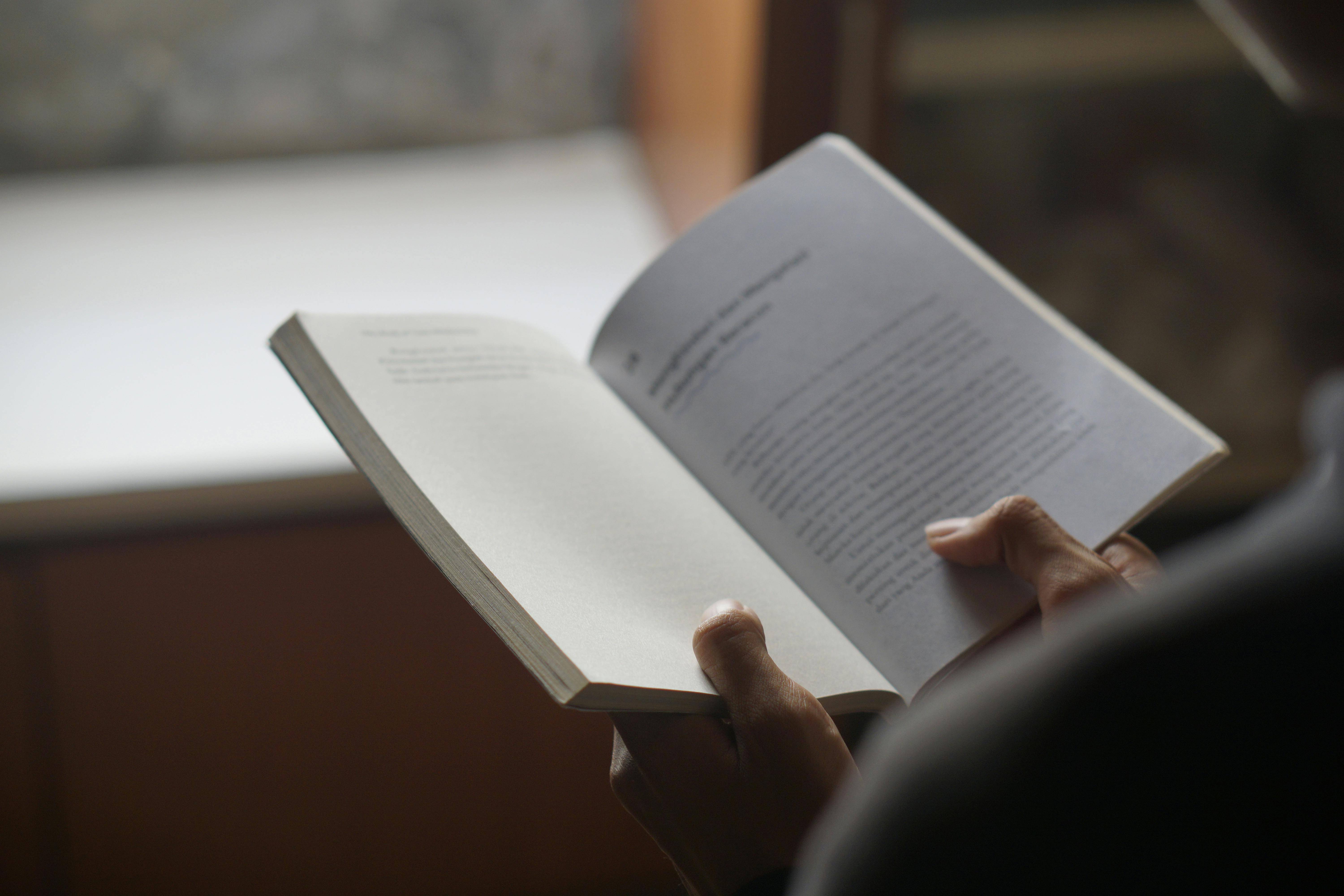 Close-up of a Person Reading an Open Book