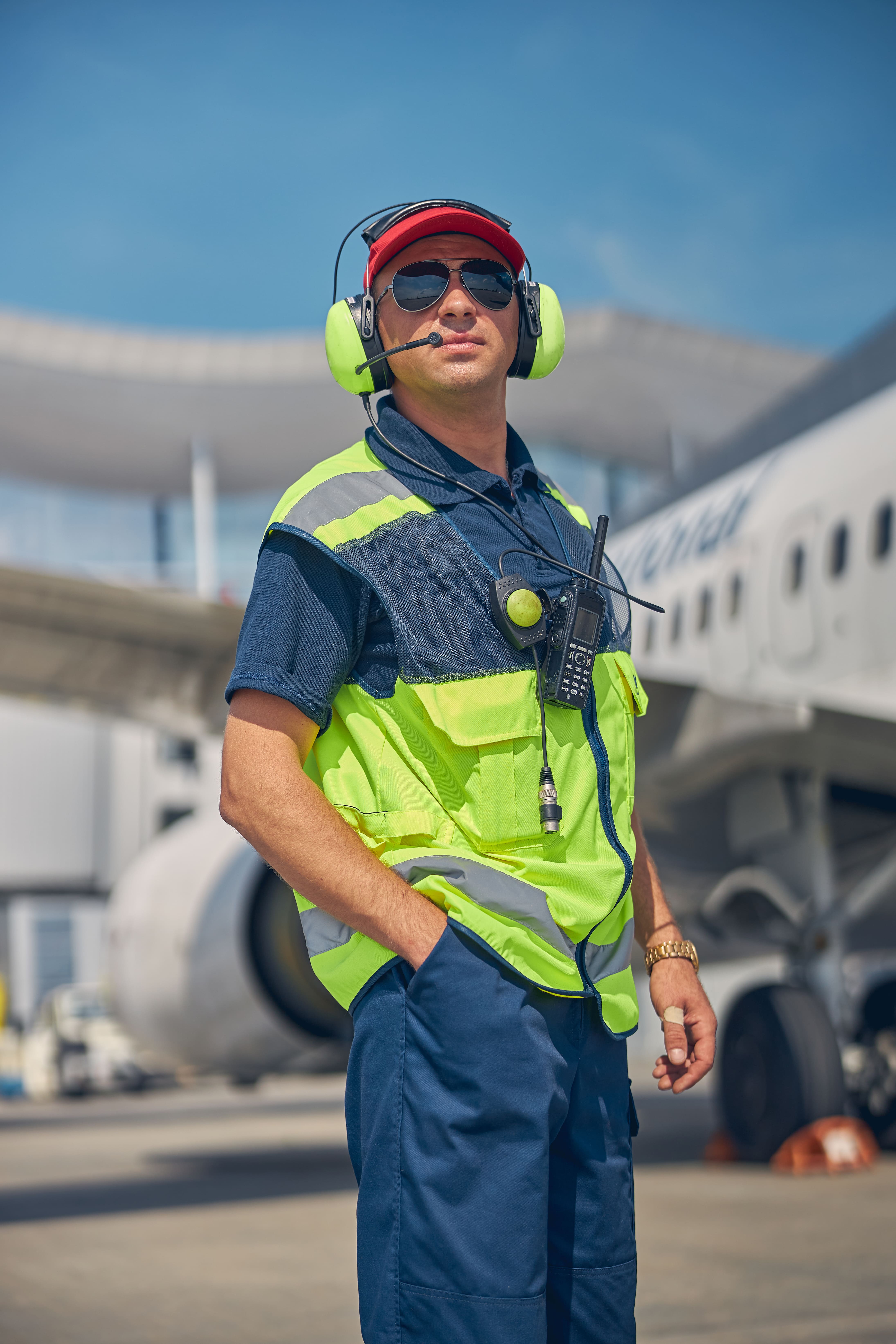 Profissional aeroportuário com postura séria e confiante em meio aos aviões.