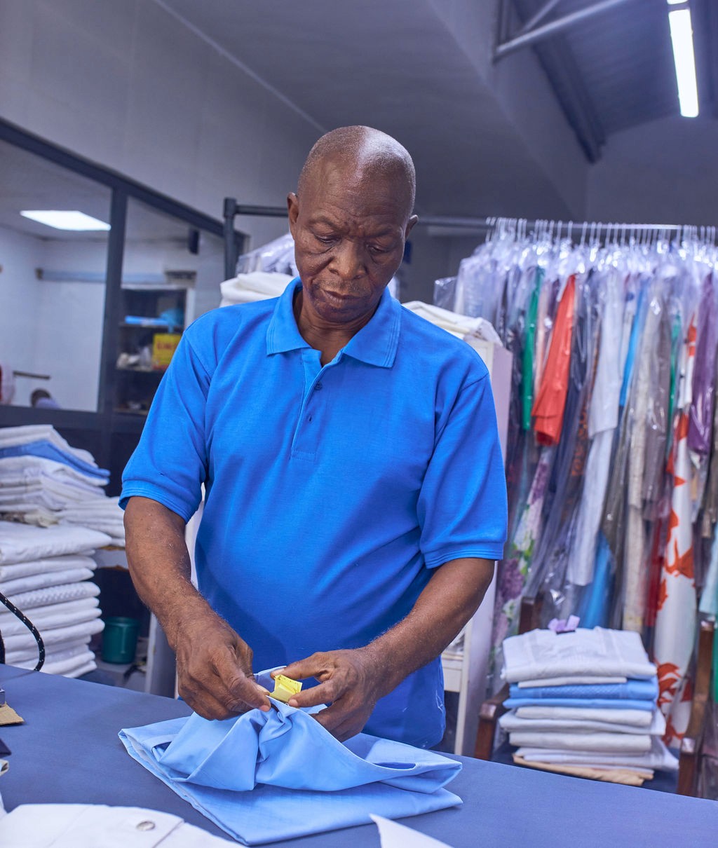 A person measuring a white shirt with a green measuring tape