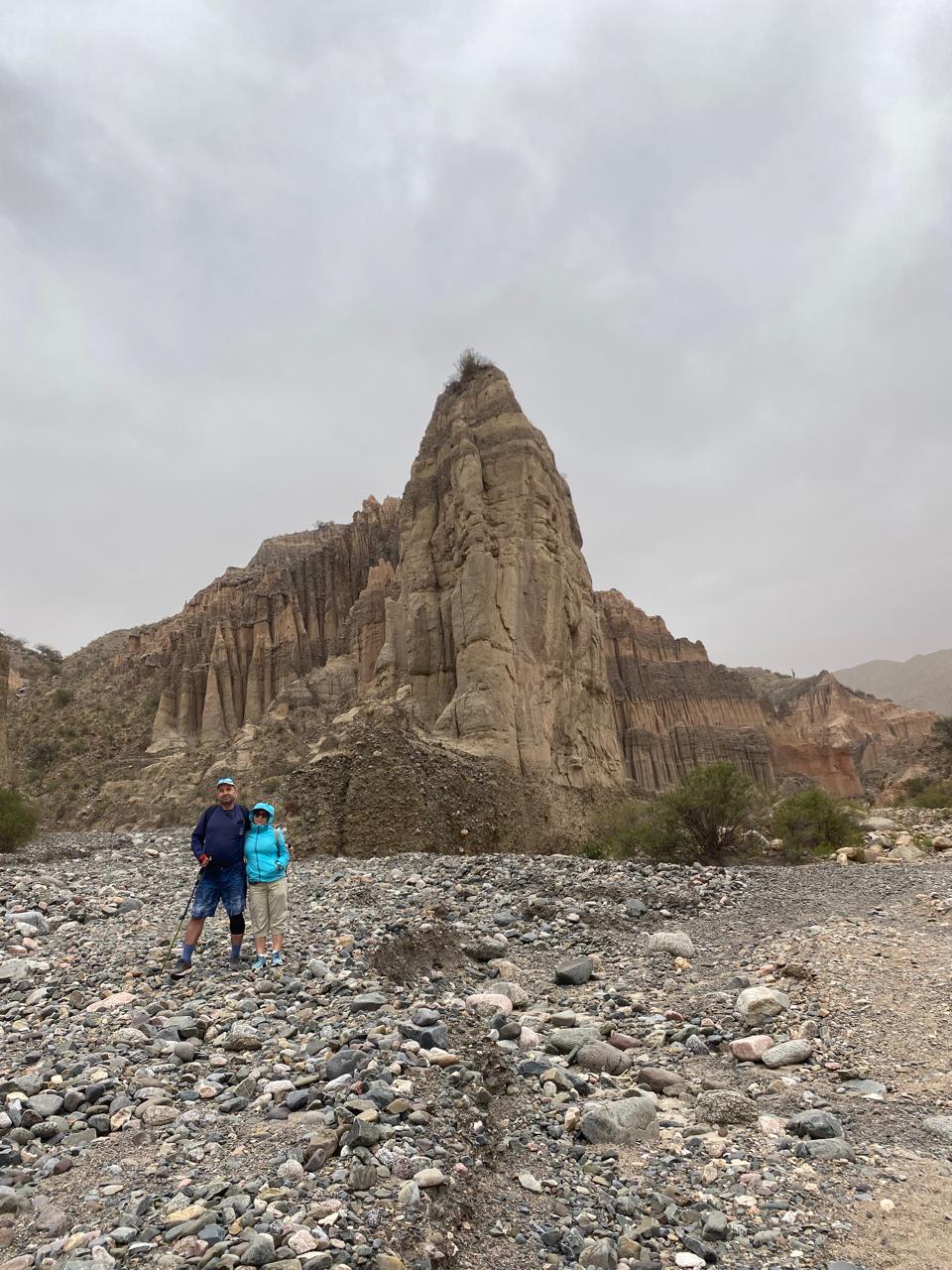 Mujer sentada sobre un tronco frente a una cascada doble en un bosque frondoso de Argentina.