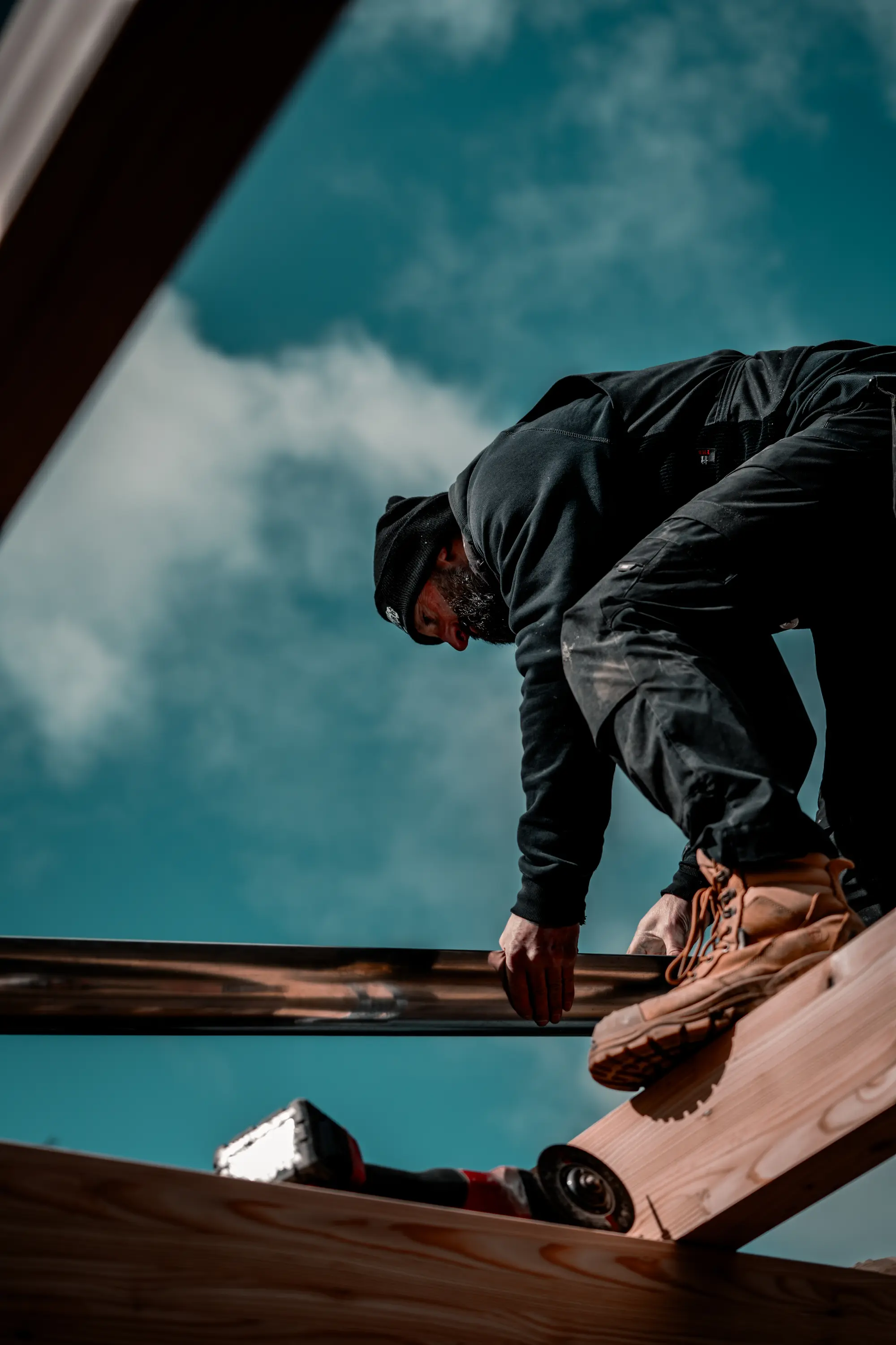 Handwerker läuft über Dachkonstruktion während Holzbauarbeiten am Gebäude