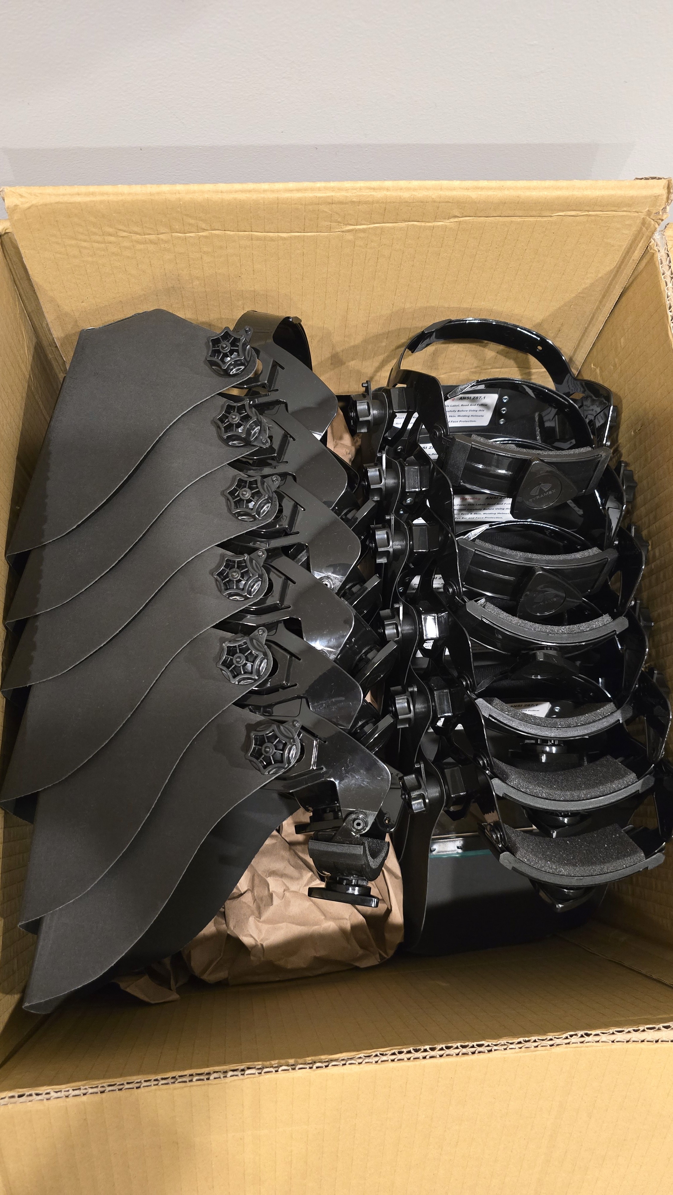 A smiling woman with her arms crossed, standing against a dark green background. She has long, dark hair.