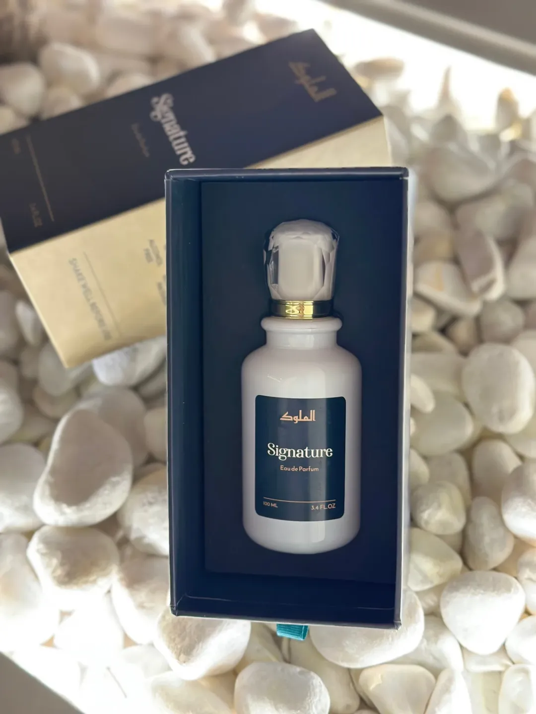 Al-Mulook Sultan perfume bottle with gold-accented label displayed on textured white stones.