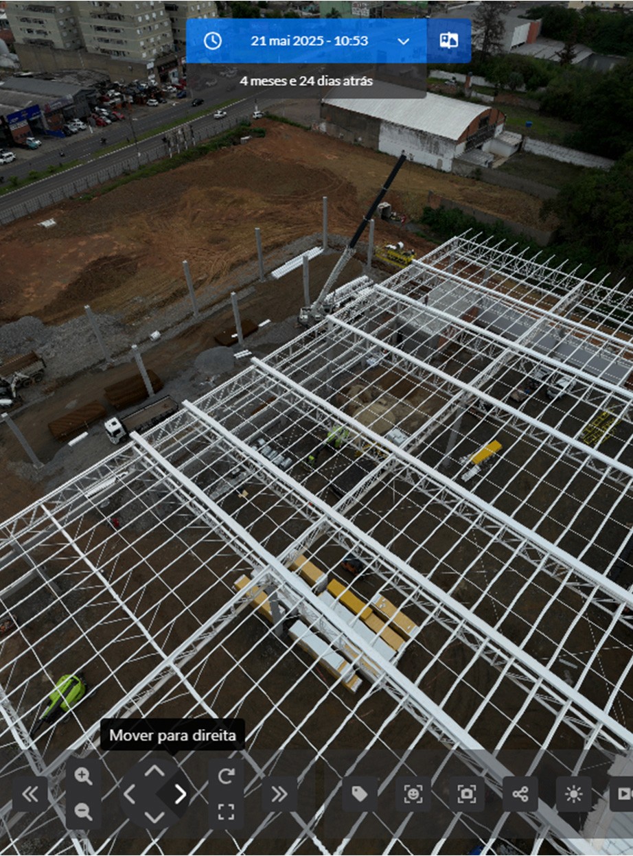 Captura de tela da plataforma Construct IN mostrando uma visão aérea de uma estrutura metálica de telhado em construção. No topo, uma barra azul indica a data da captura (21 de maio de 2025), permitindo a navegação temporal pelo progresso da obra.