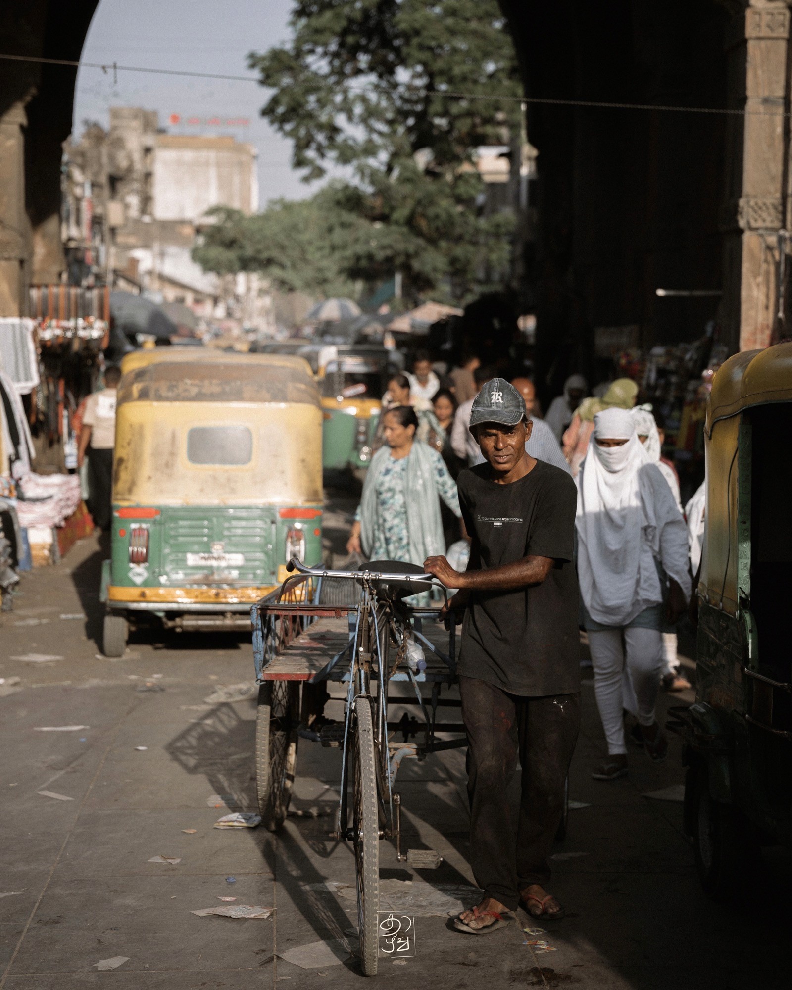 Autorickshaws and a cycle rickshaw sharing a narrow street