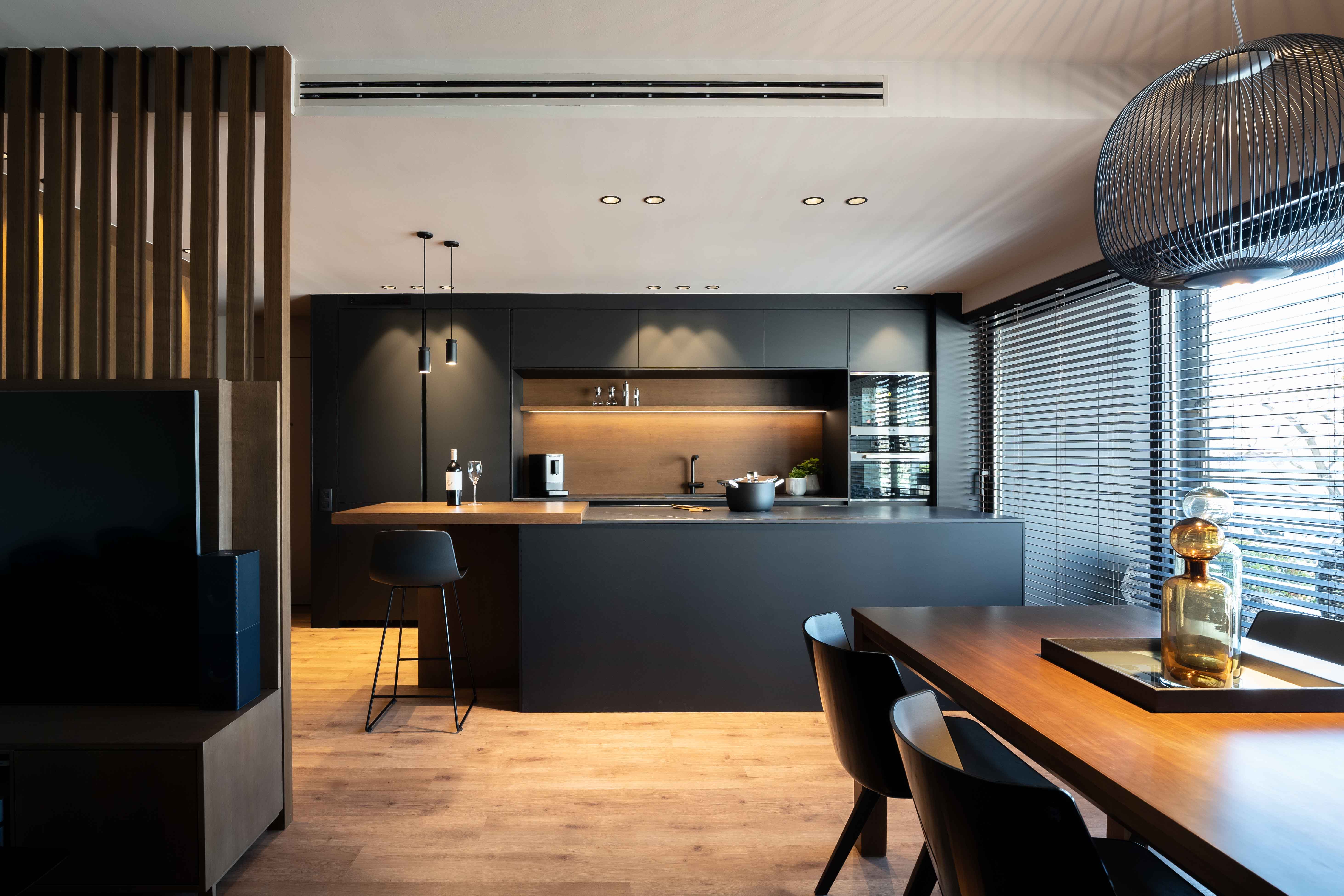 Cocina-comedor abierta de estilo oscuro con muebles y encimera de acabados negros