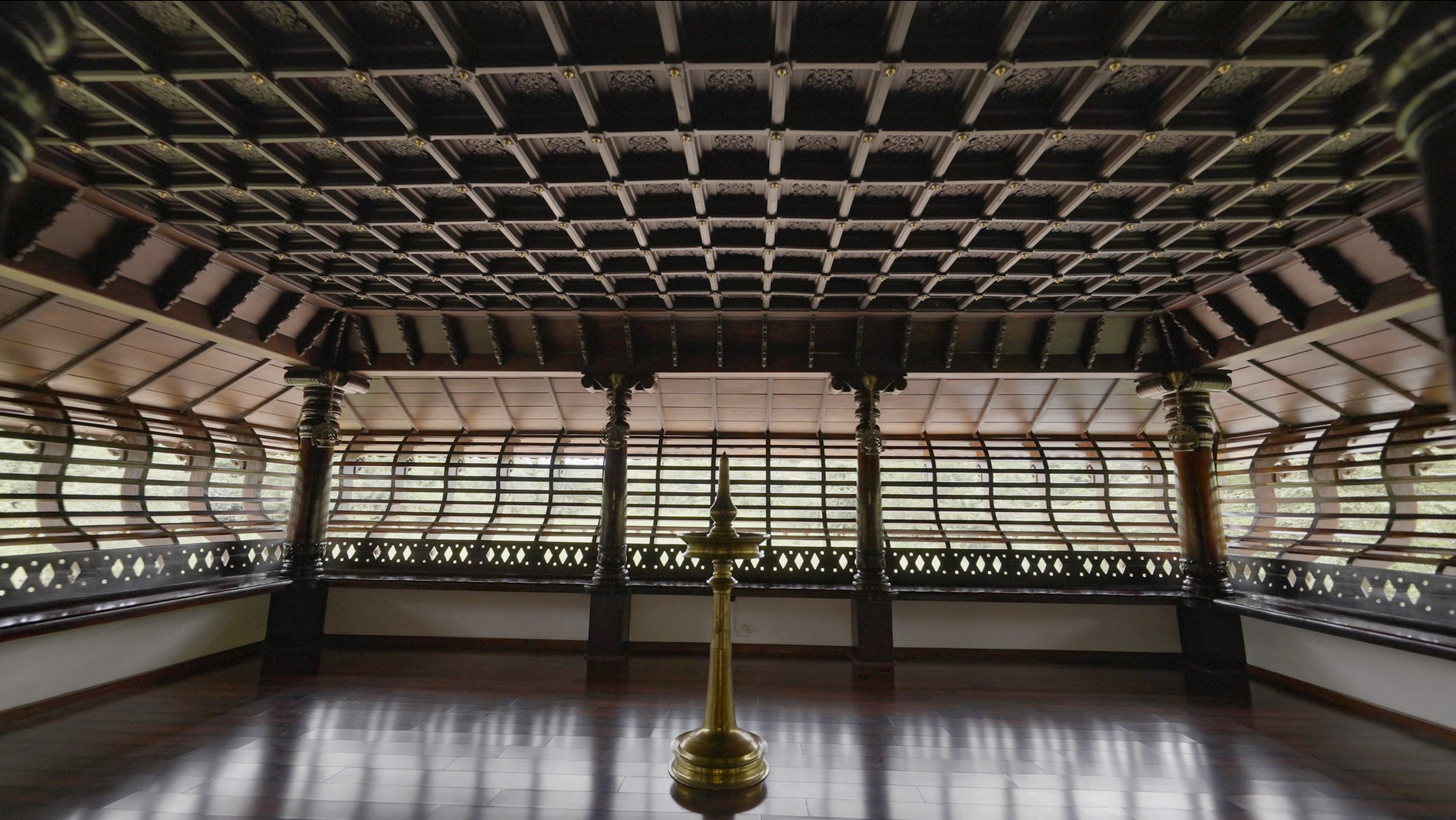 A winding road cuts through rocky terrain, surrounded by patches of green grass and illuminated by sunlight.