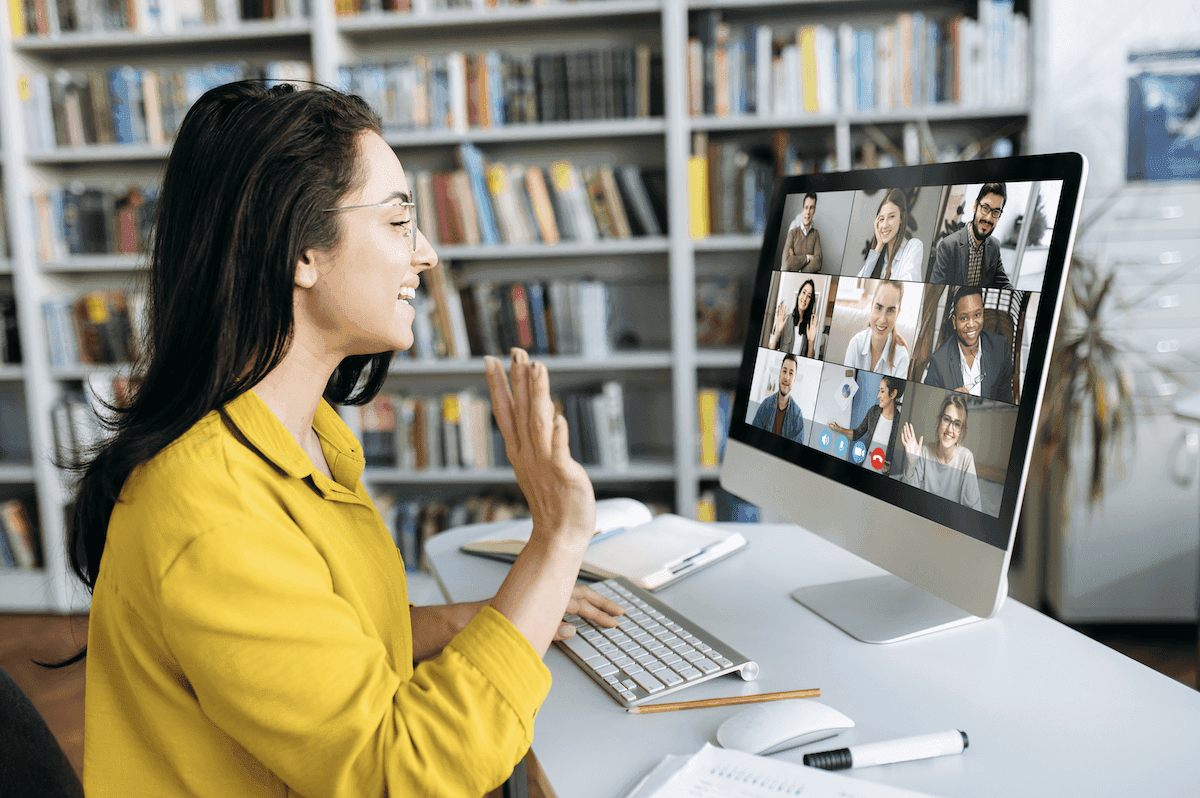 customer onboarding: Smiling woman waving her hand during a video conference