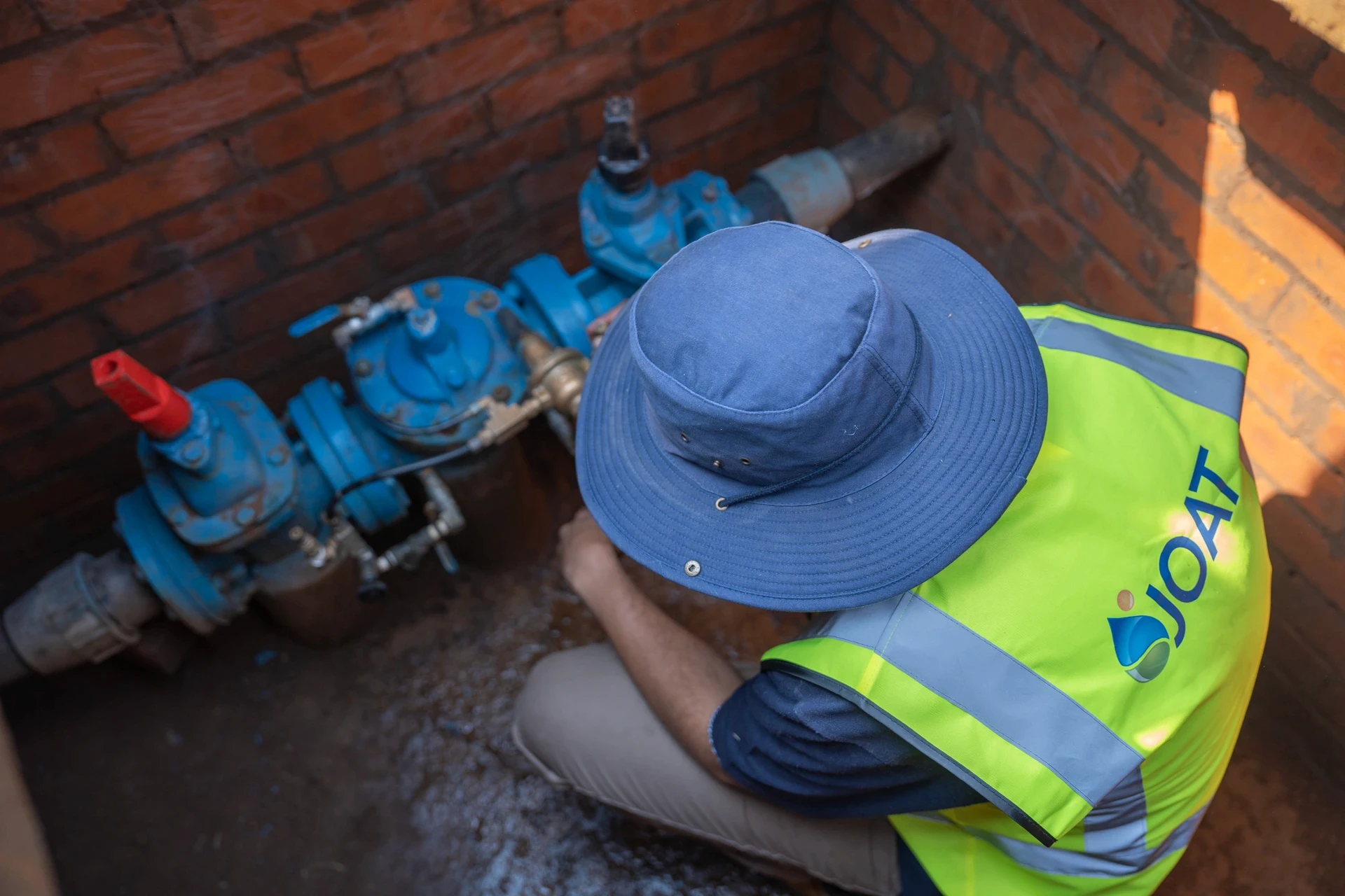 JOAT technician in hi-vis working on pressure reducing valves inside an underground brick chamber