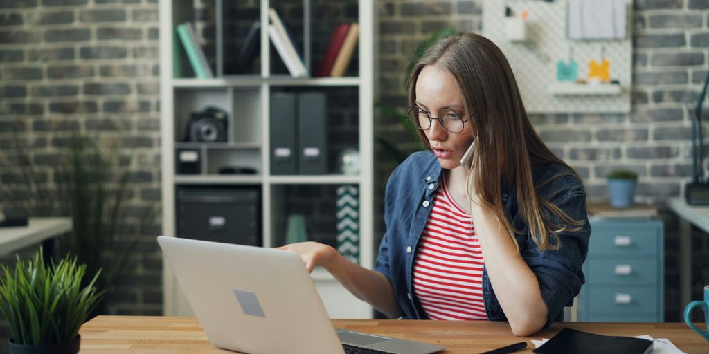 a woman sitting at a table using a laptop computer