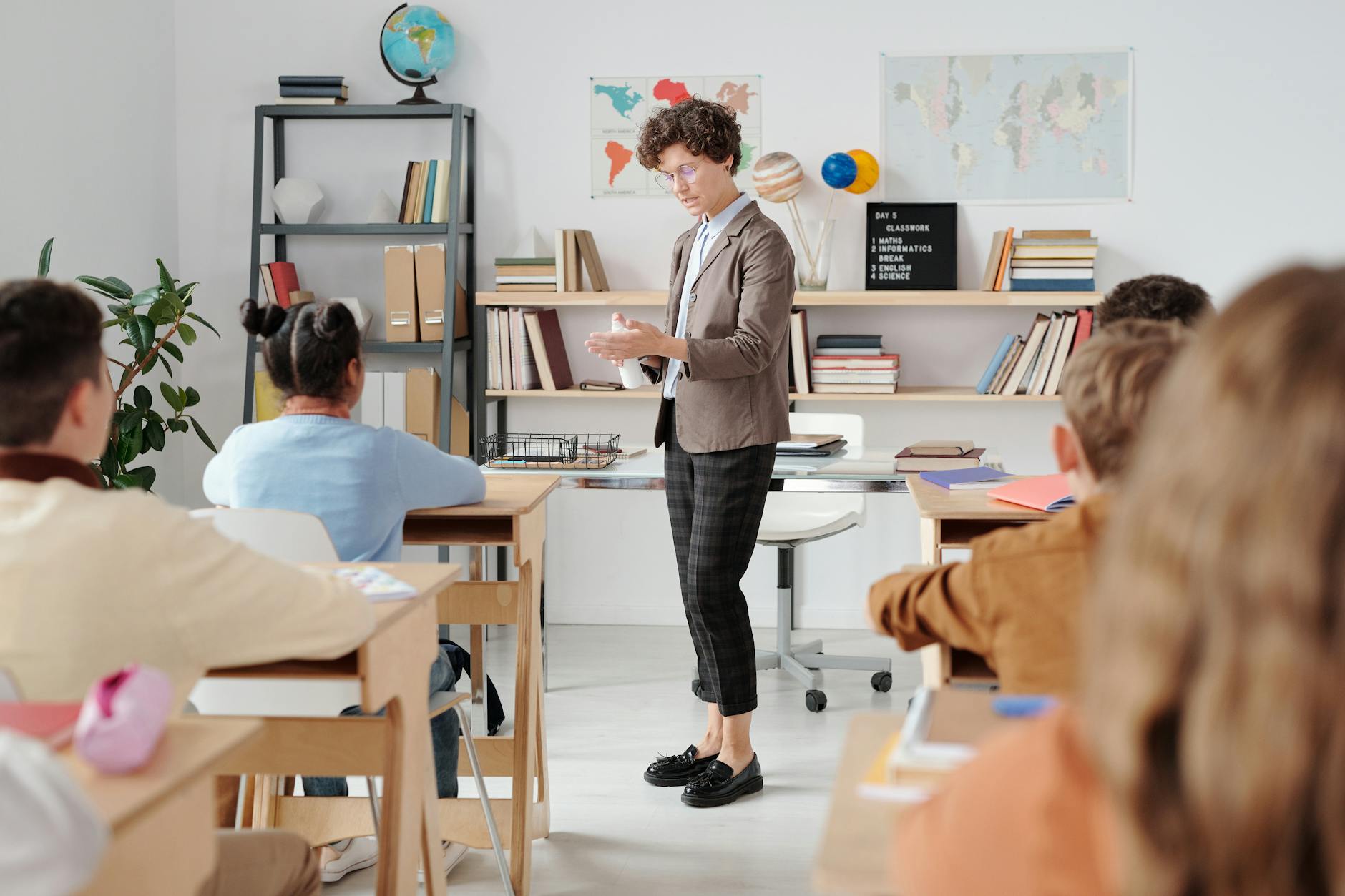 A teacher uses a hand signal to quietly transition students from group work back to their individual desks.