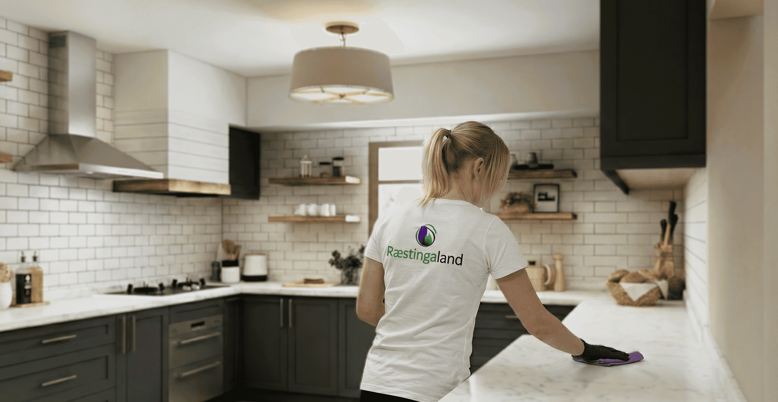 Starfsmaður Ræstingaland að þurrka af eldhúsborðplötu í nútímalegu eldhúsi.