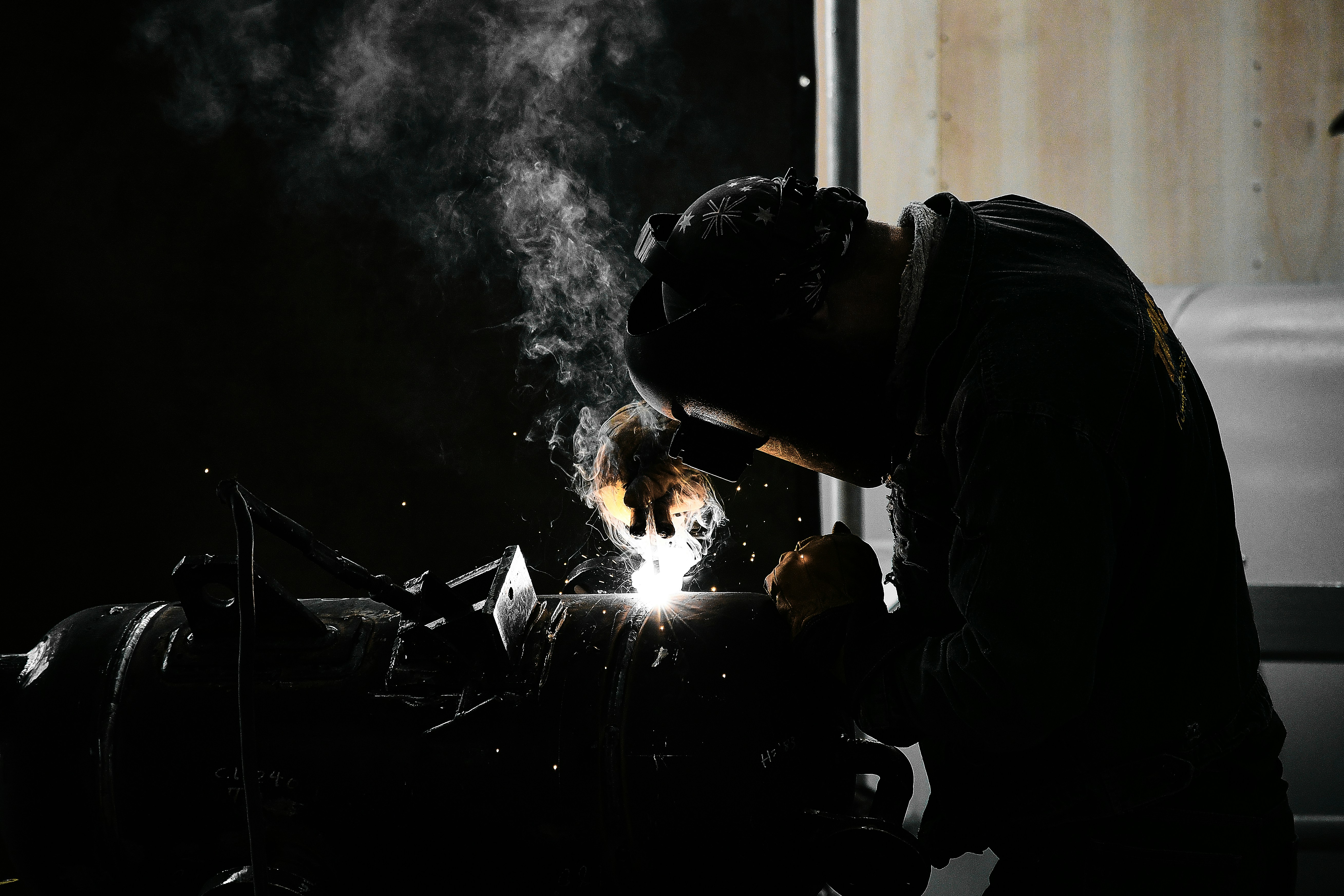 A man welding a piece of metal in a dark room