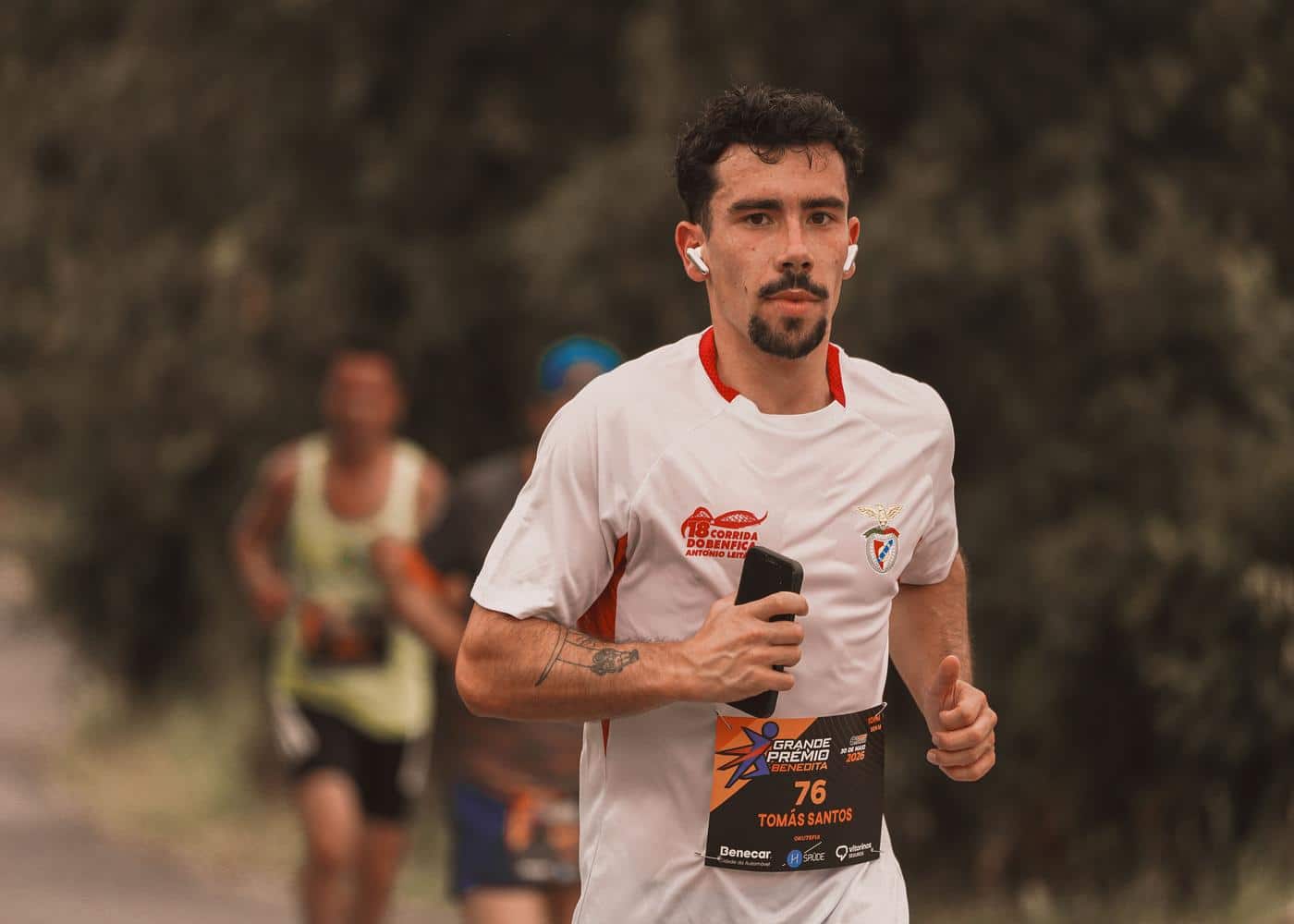 Man running in marathon holding smartphone in one hand