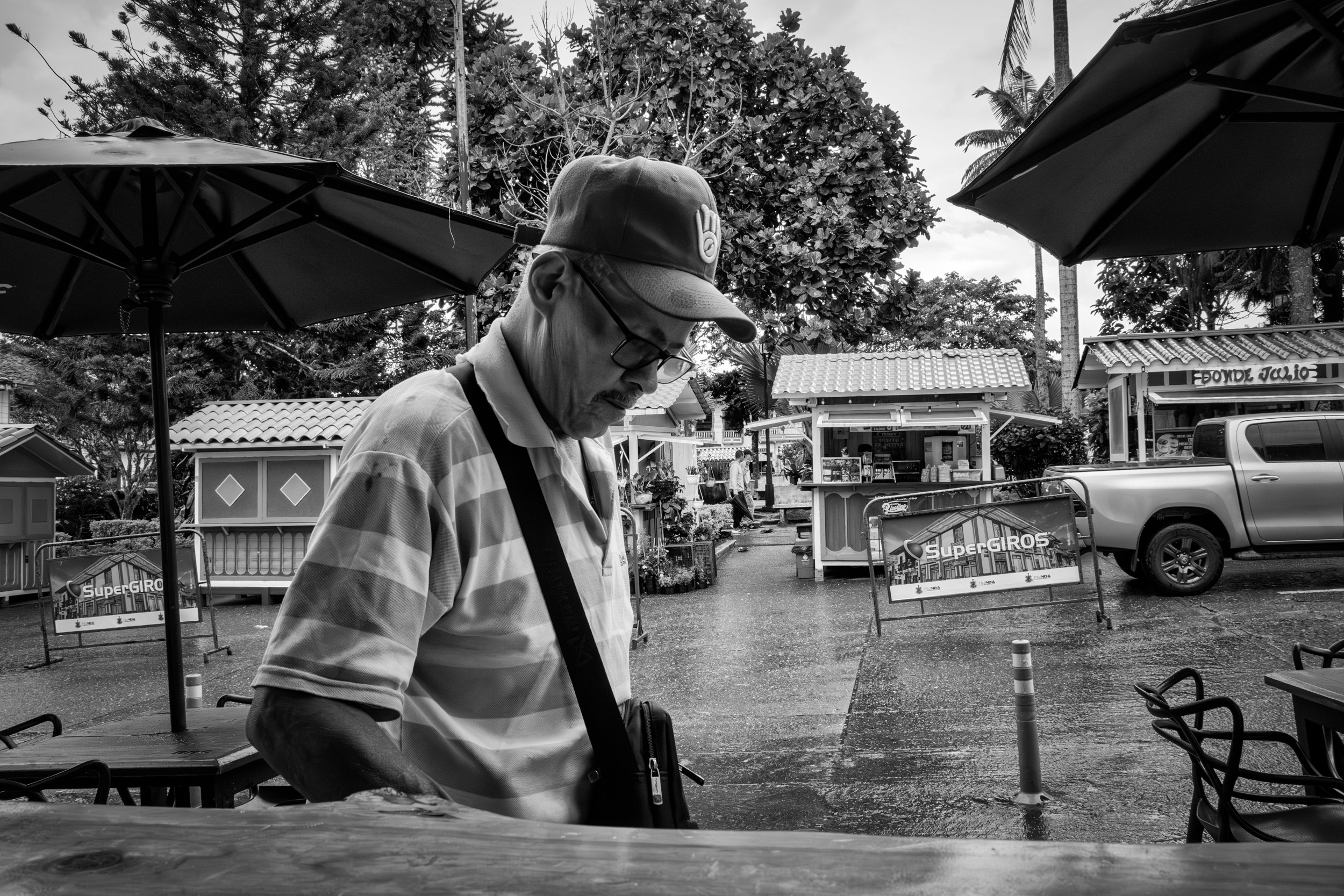 Rainy street scene with people passing by a bar window.