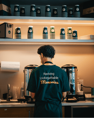 Smiling barista holding green cup at coffee machine