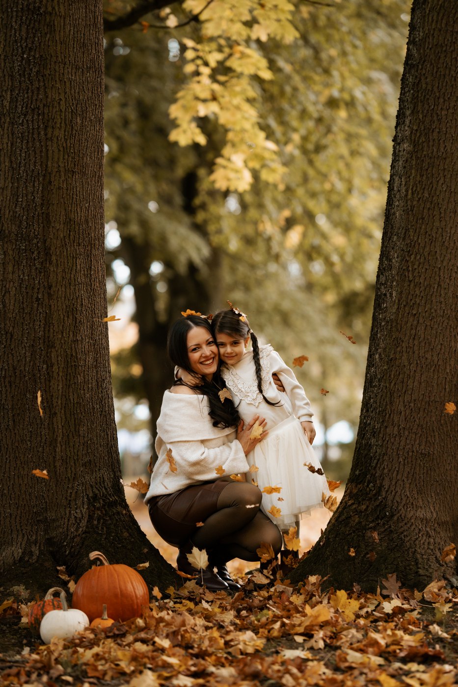 Mutter und Tochter unter einem Baum im Herbstlaub