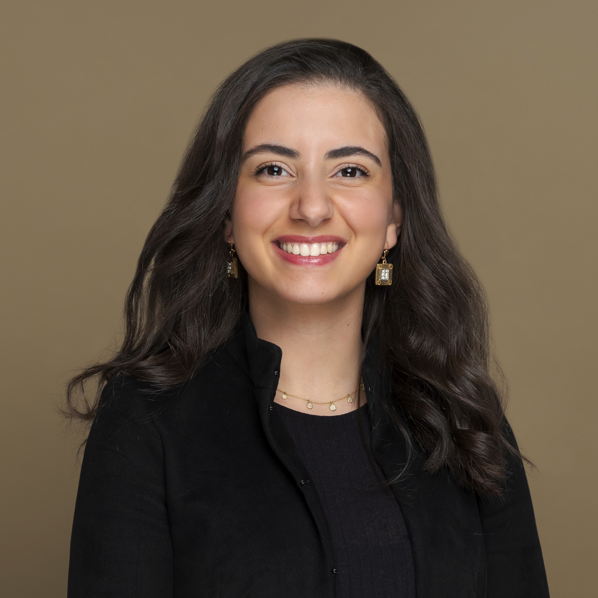 A person with shoulder-length blonde hair wearing a black newsboy cap and a black sweater.