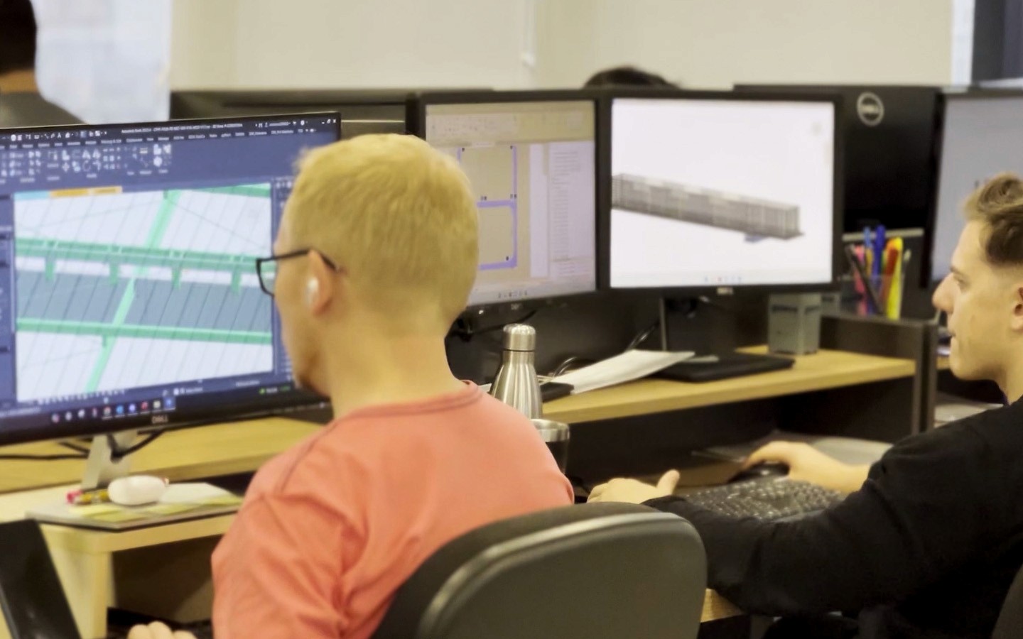 Dois especialistas trabalhando em uma estação de trabalho com múltiplos monitores. Eles analisam e processam dados de nuvem de pontos e modelos 3D, transformando a Captura da Realidade bruta em informações acionáveis para engenharia e arquitetura.