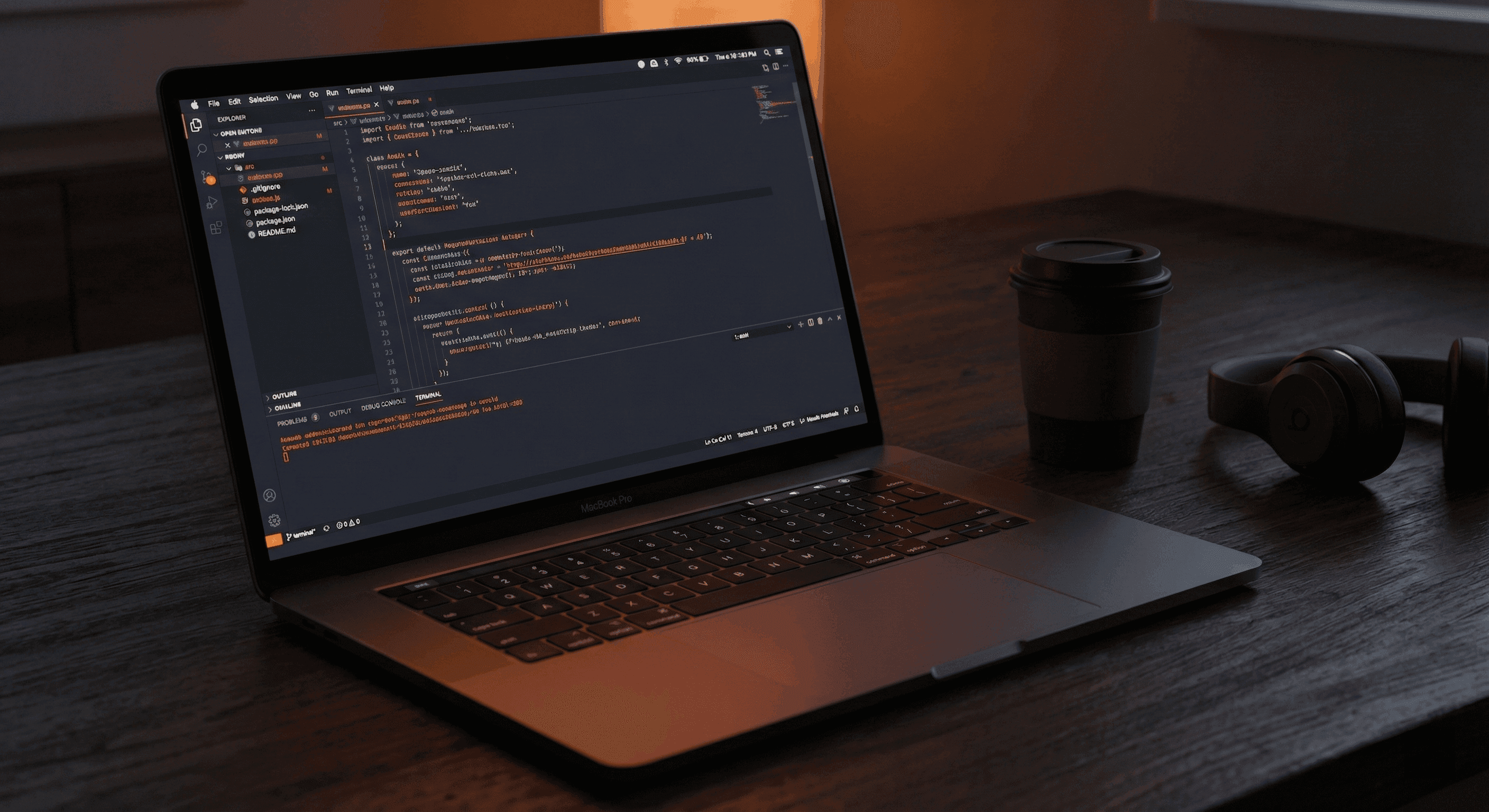 Laptop with code on screen, coffee cup, and headphones on a wooden desk.