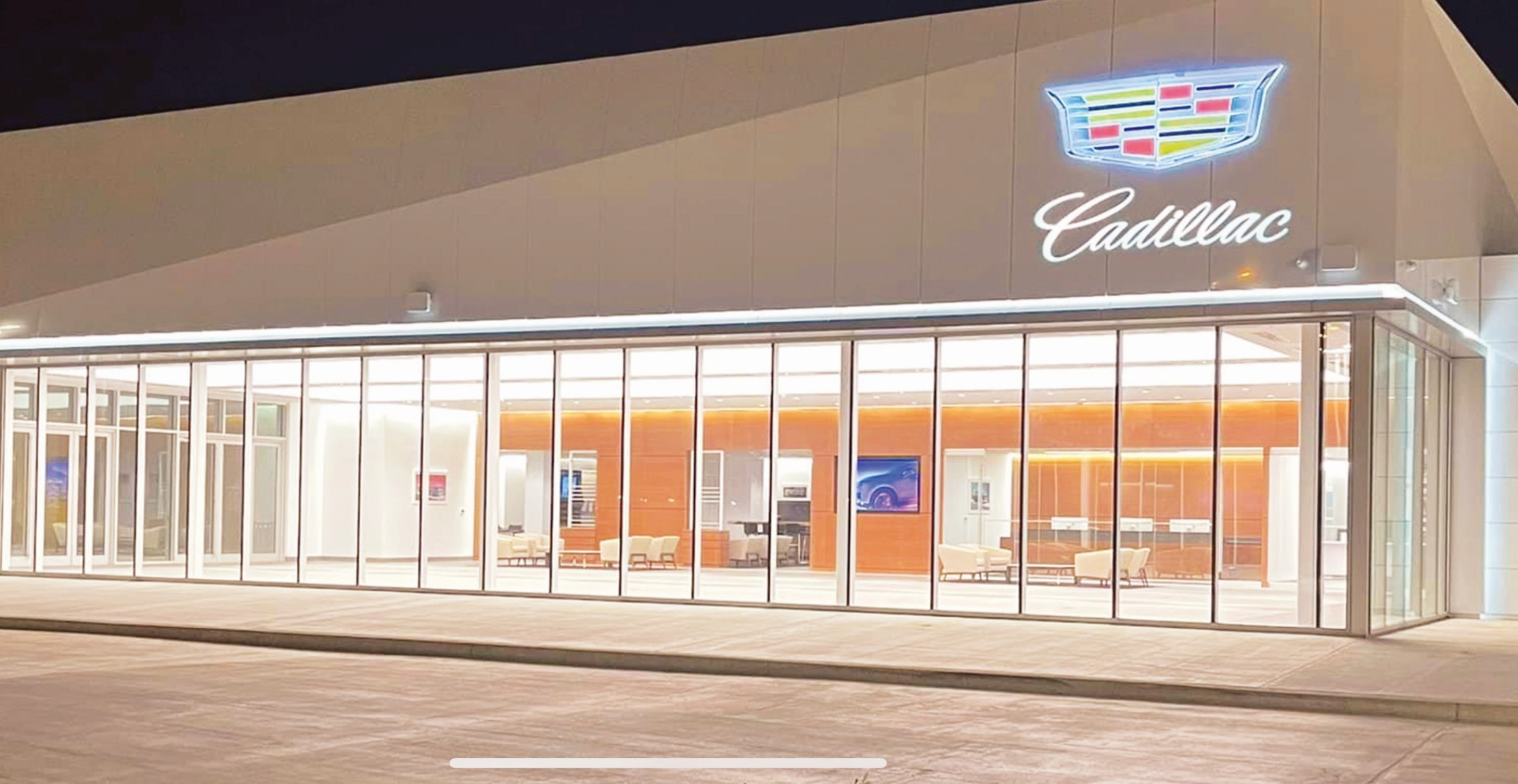 Cadillac dealership with lit emblem and showroom.
