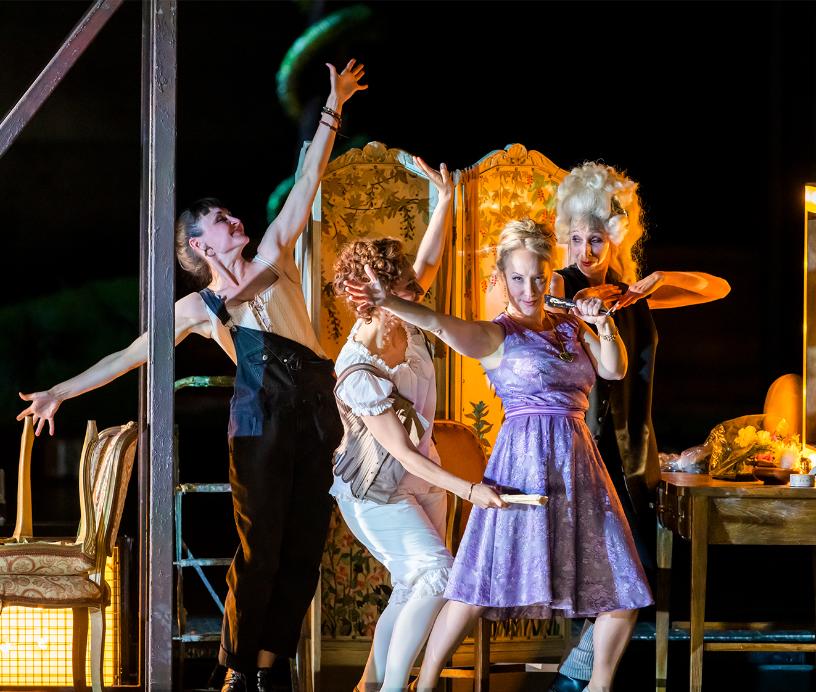 Four women striking playful poses backstage in a lively scene from Cosi fan tutte.