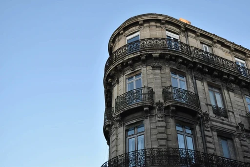 Rounded corner of a Haussmann-style building with ornate wrought iron balconies in France