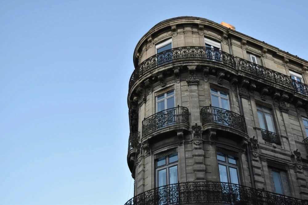 Rounded corner of a Haussmann-style building with ornate wrought iron balconies in France