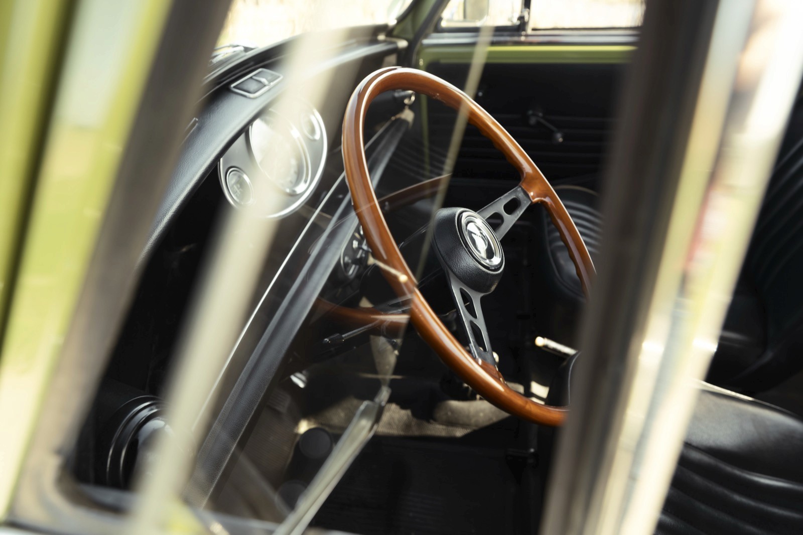 Close-up of an old vehicle's interior, focusing on the steering wheel and dashboard. Dusty and aged appearance.