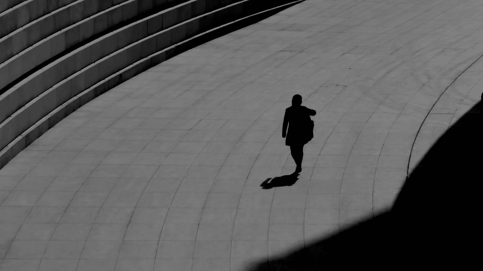 A solitary figure crossing a geometric architectural space