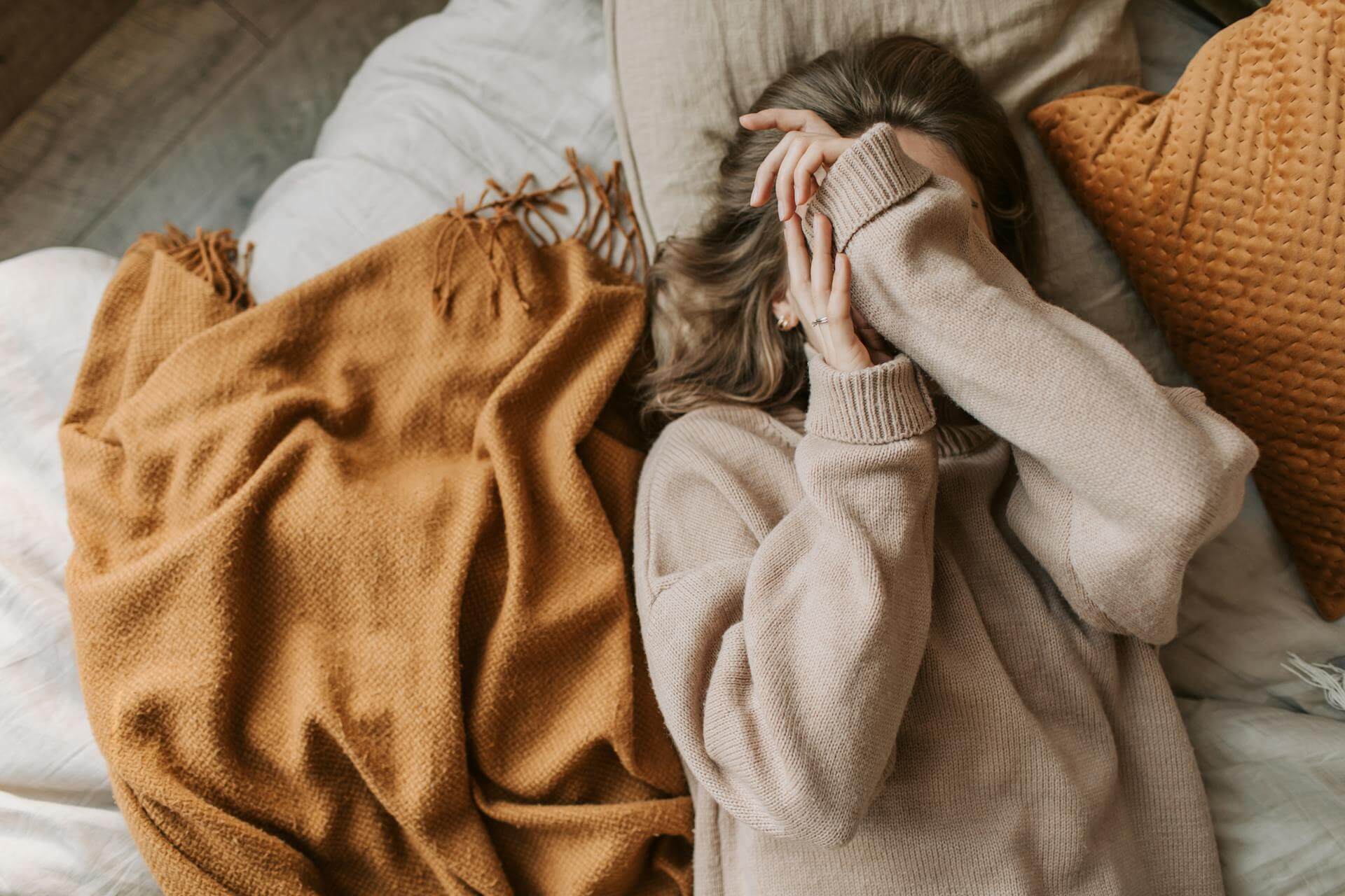 A woman reclines on a bed, covered with a cozy blanket, exuding a sense of relaxation and comfort