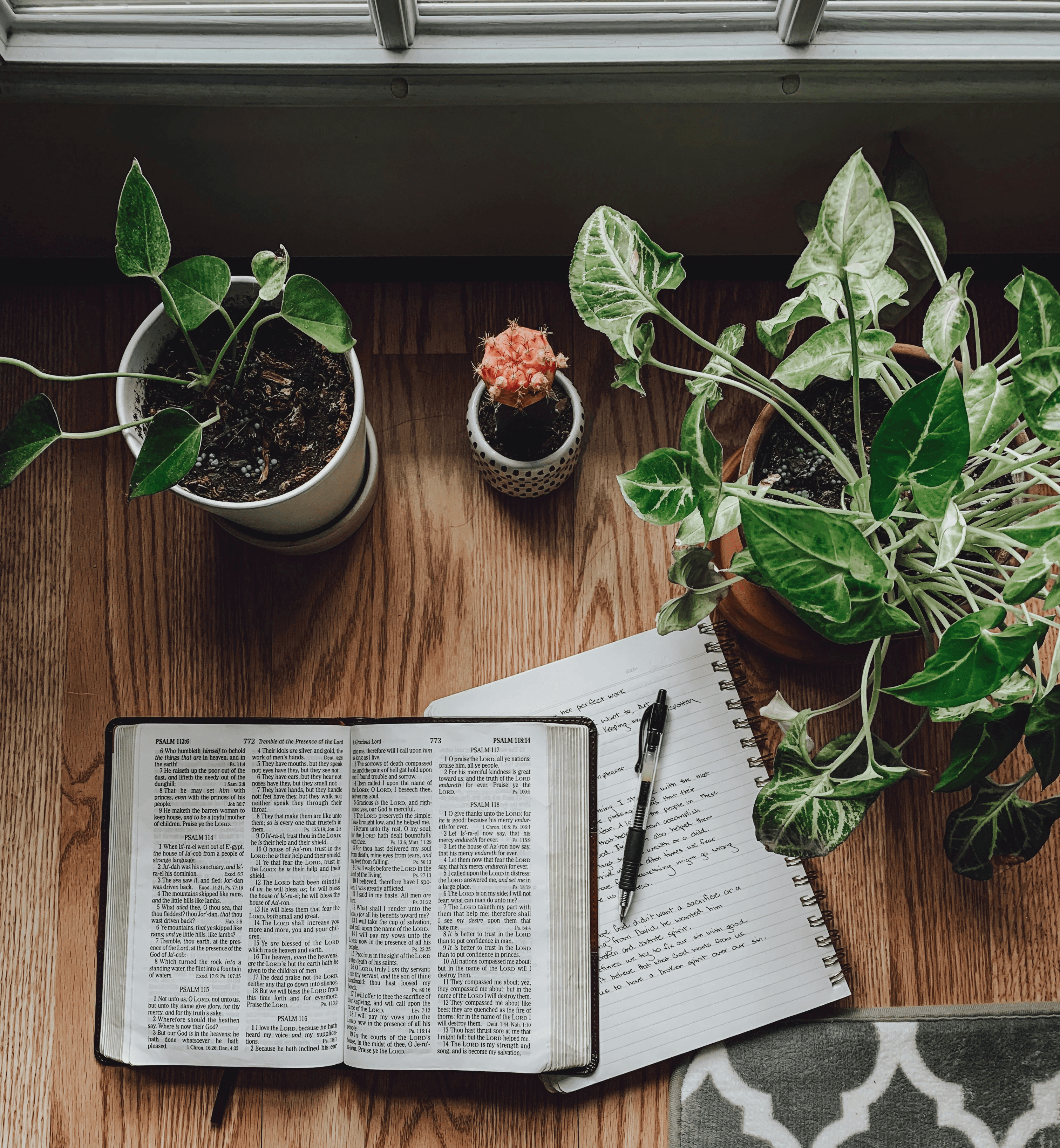 An open bible laid on top of a notebook with a pen sitting nearby