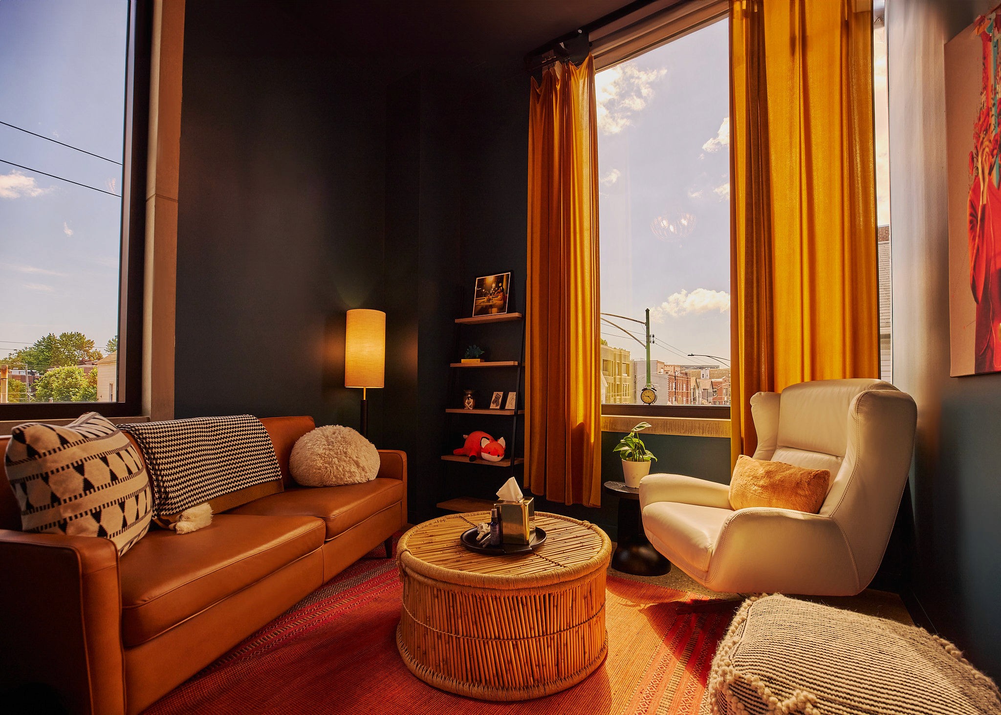 A crow perched on a pipe against an orange sky.