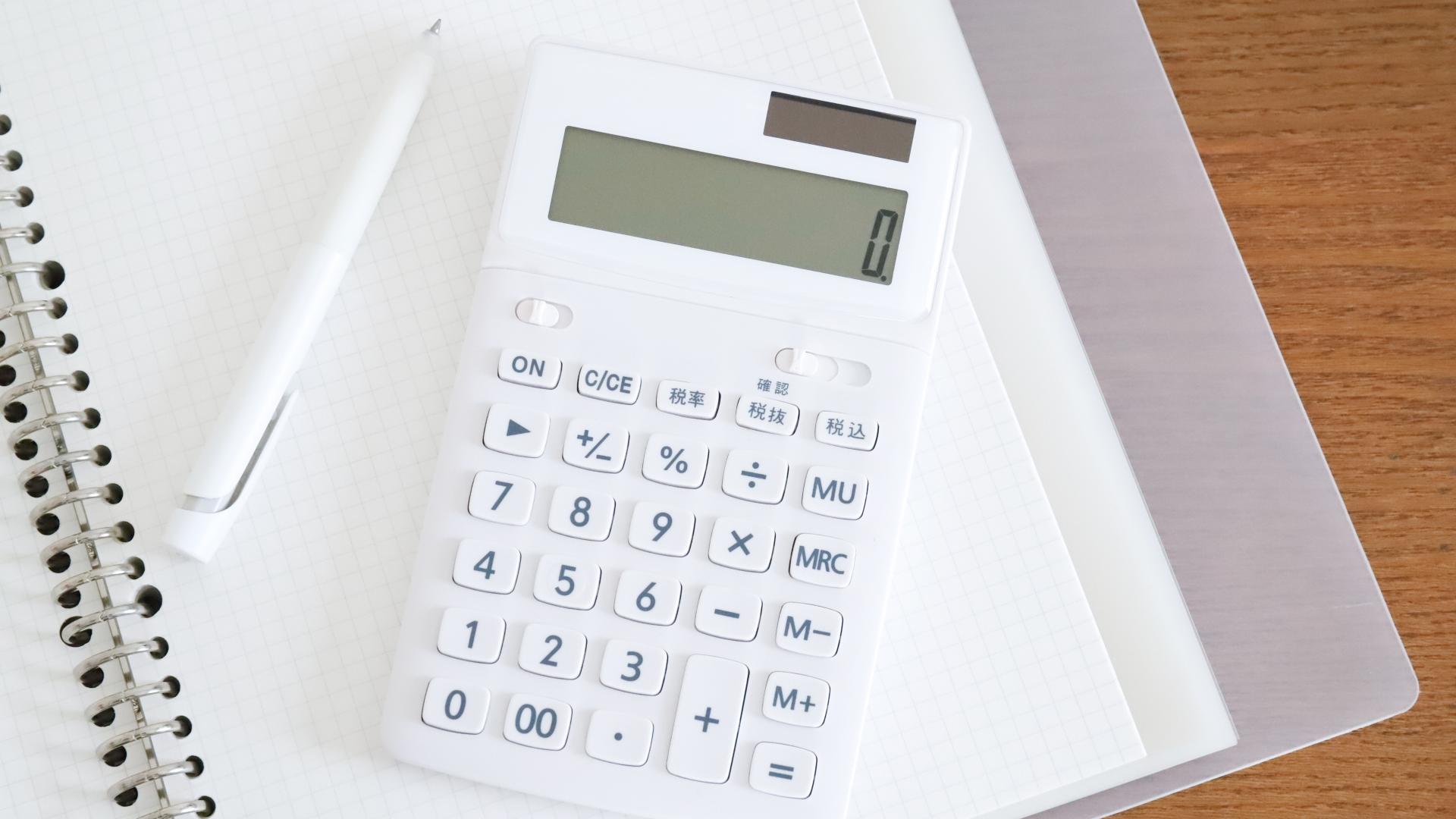 電卓とノート、ペンが並ぶ机上