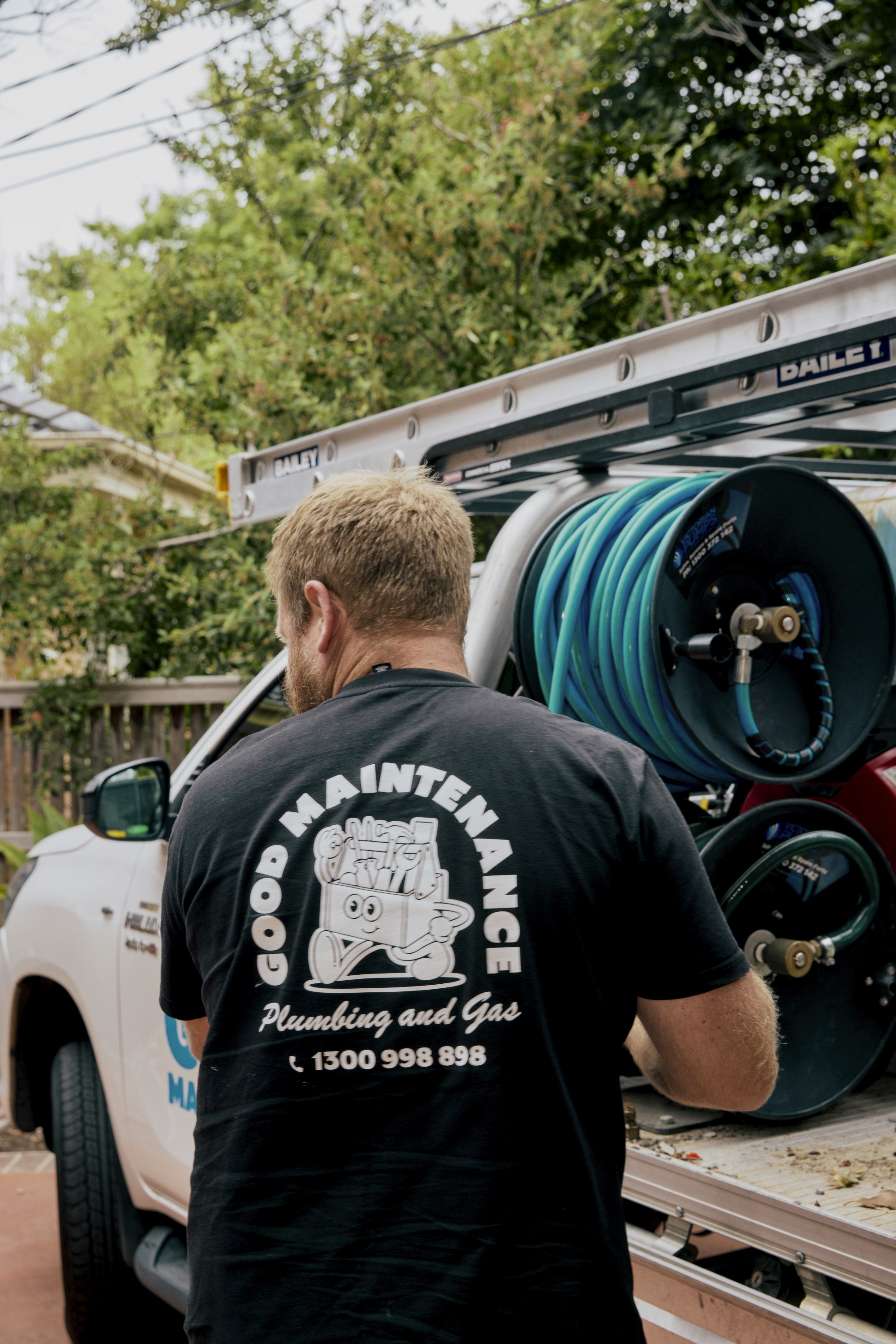 Good Maintenance Plumber uncoiling a hose from the back of a company ute.
