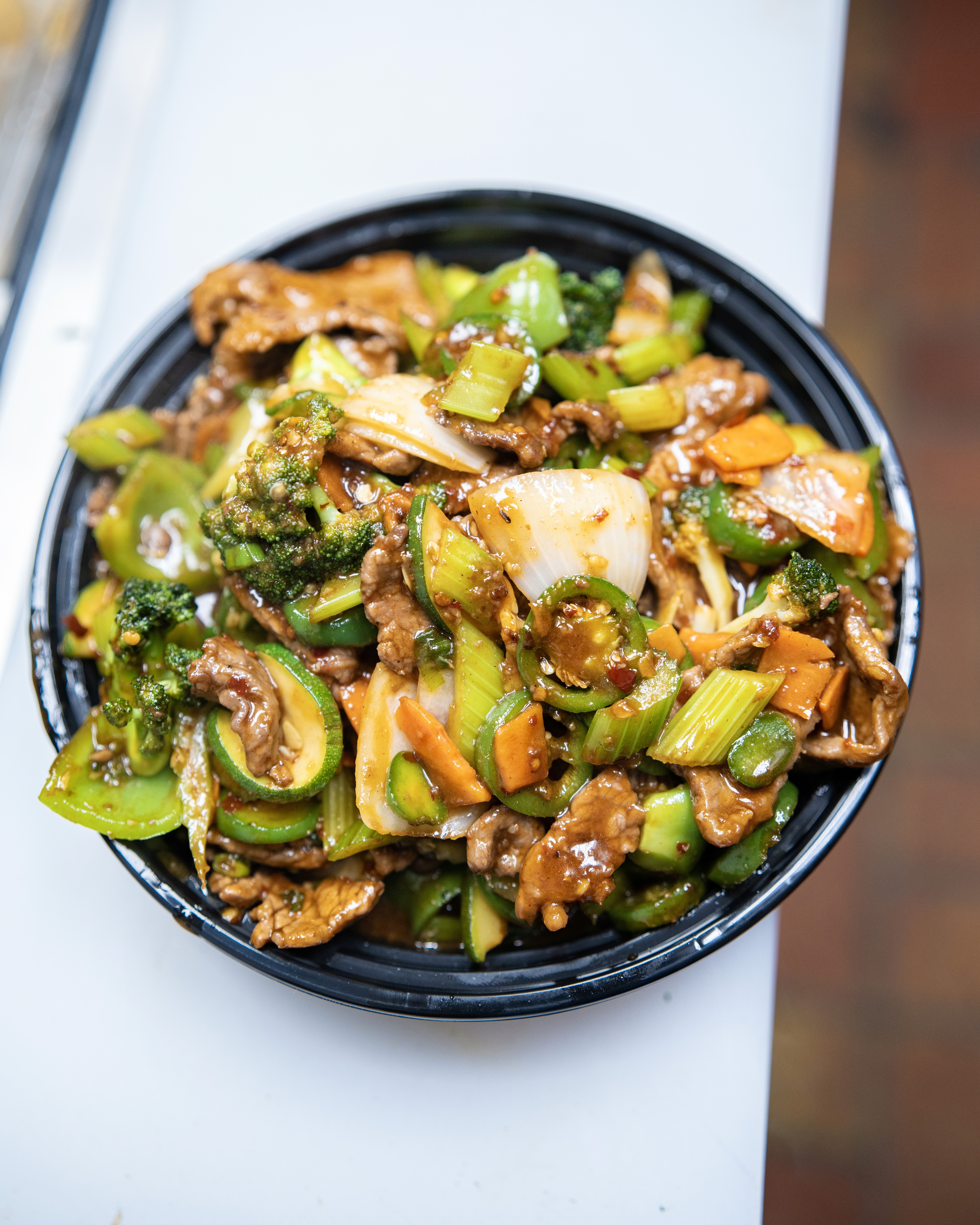 A beautifully plated dish featuring shrimp, colorful vegetables, and garnishes, set in a modern restaurant.