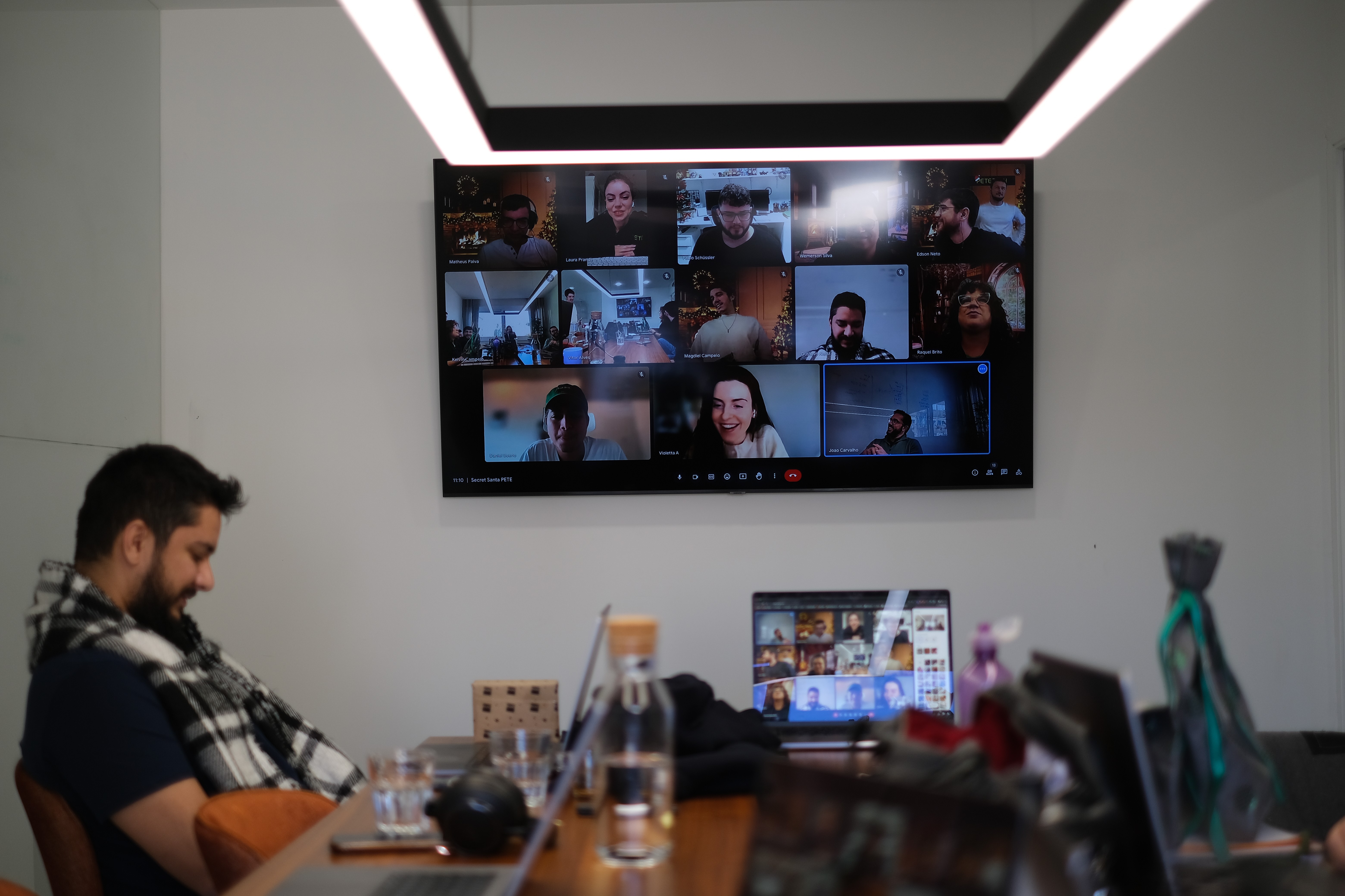 One team member in the office on a video call with multiple remote colleagues displayed on the TV screen