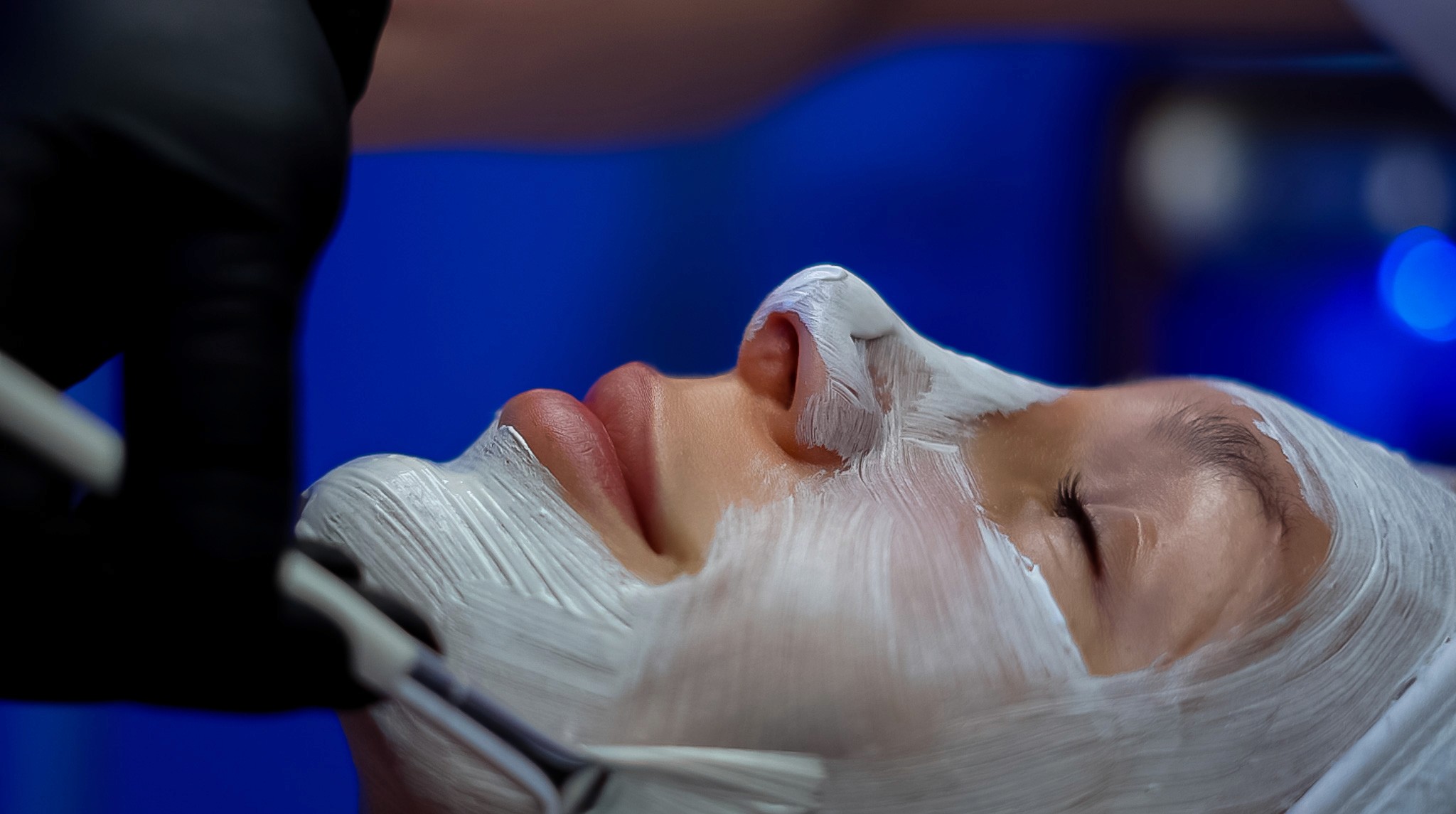 Smiling woman using a rose quartz Gua Sha stone and face roller for a facial massage