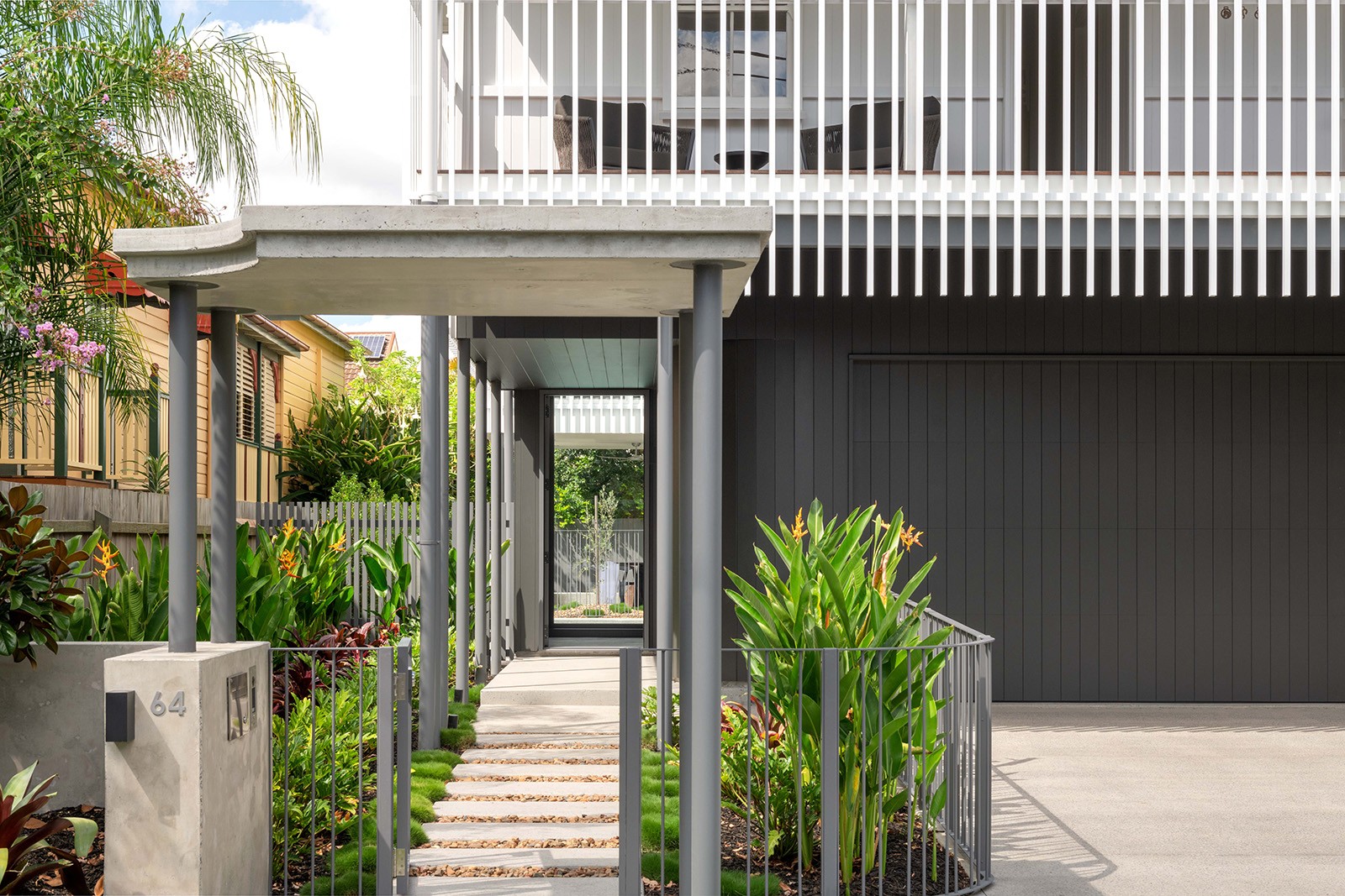 Entry sequence to The Stables showing a covered walkway through planting, leading to the courtyard-focused home and reinforcing the project’s strong indoor–outdoor connection.